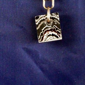 Square pendant with abstract black pattern.