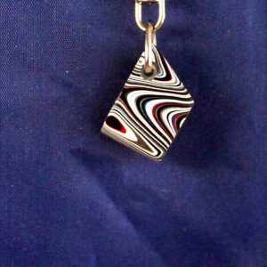 Abstract swirl-patterned keychain on blue background.