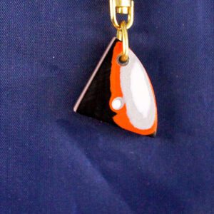 Triangular pendant with orange and black design.