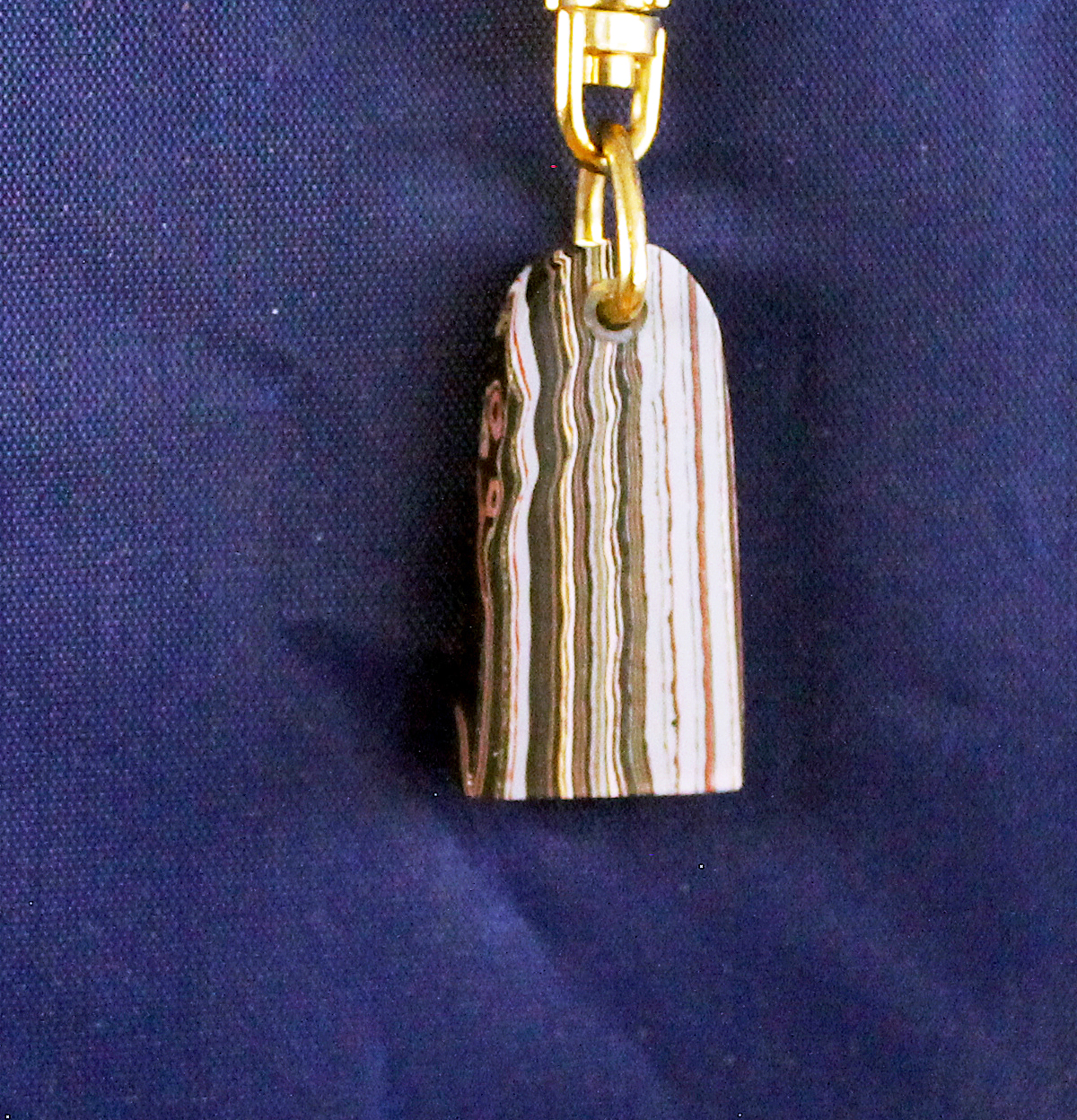 Striped pendant with gold clasp on blue.
