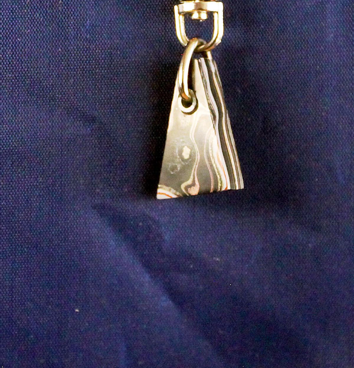 Metal keychain on dark blue fabric background.