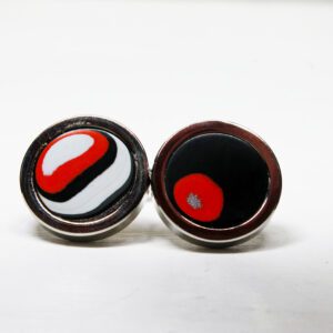 Round black and red cufflinks on display.