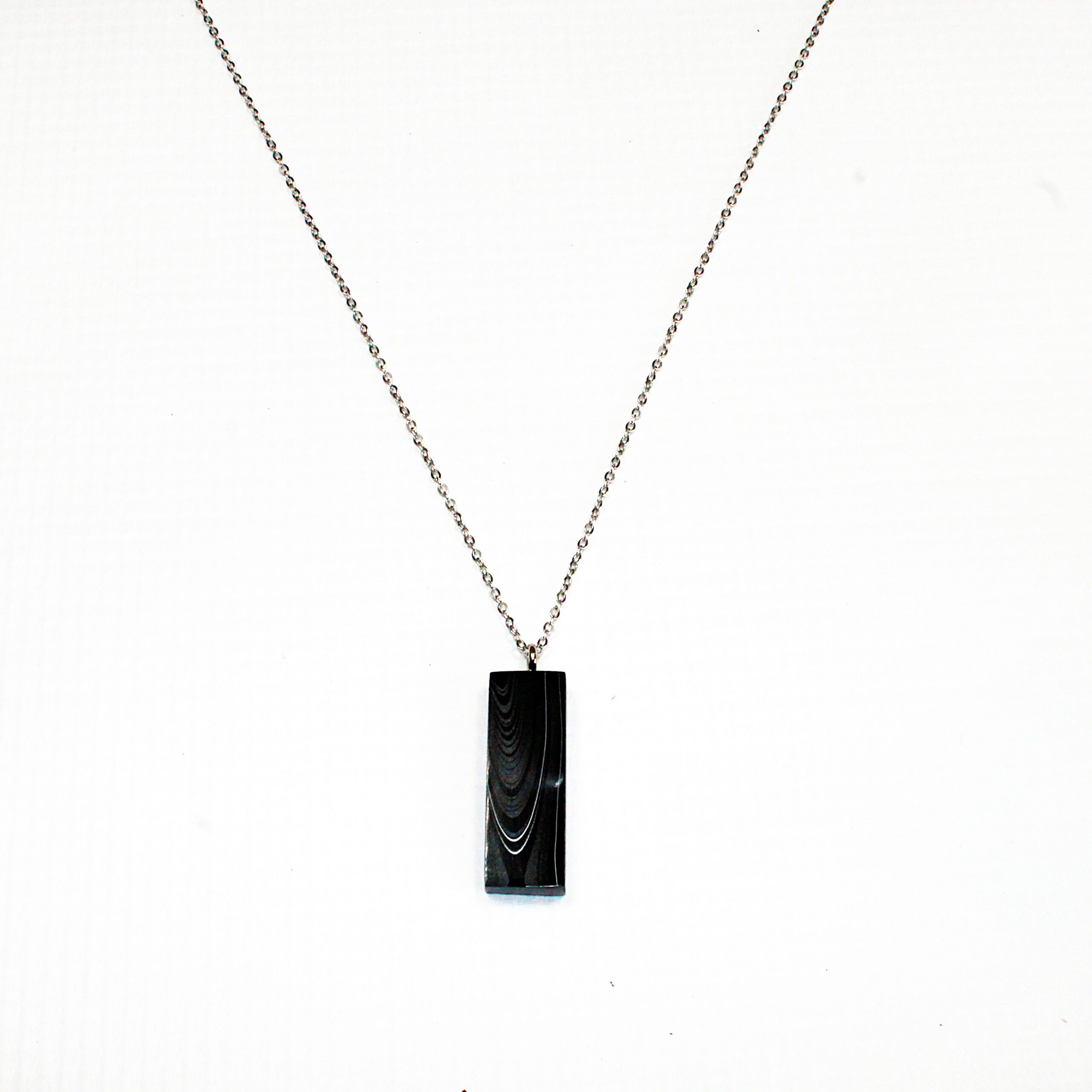 Silver chain with black rectangular pendant.