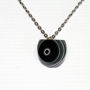 Black circular pendant on silver chain.