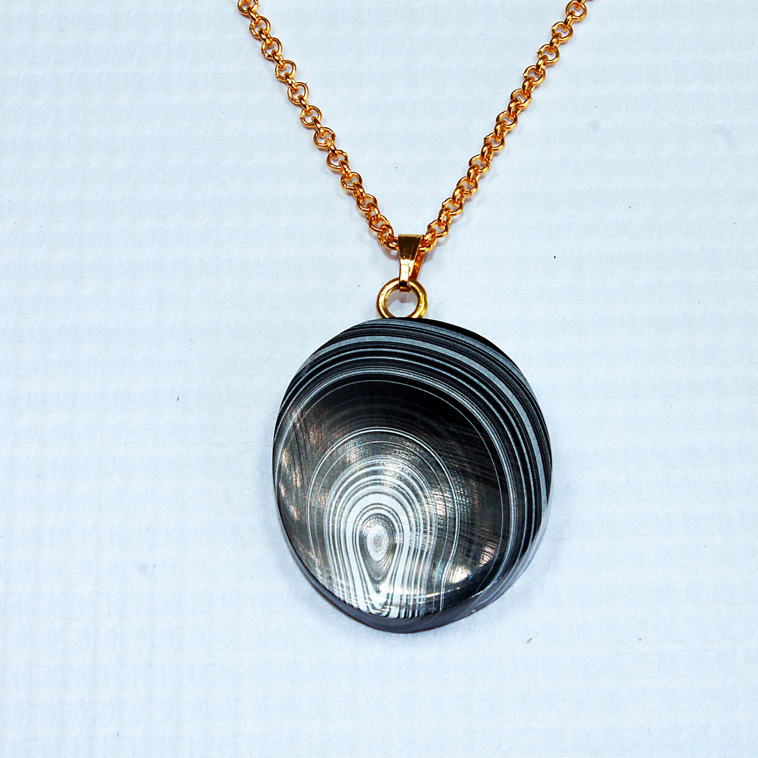 Pendant with striped stone on gold chain.