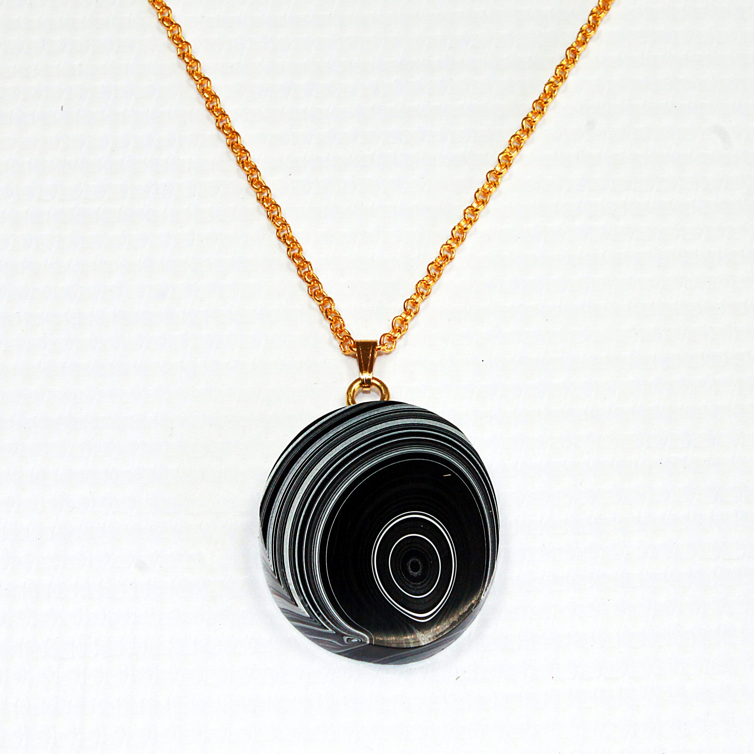 Gold chain with round black pendant.