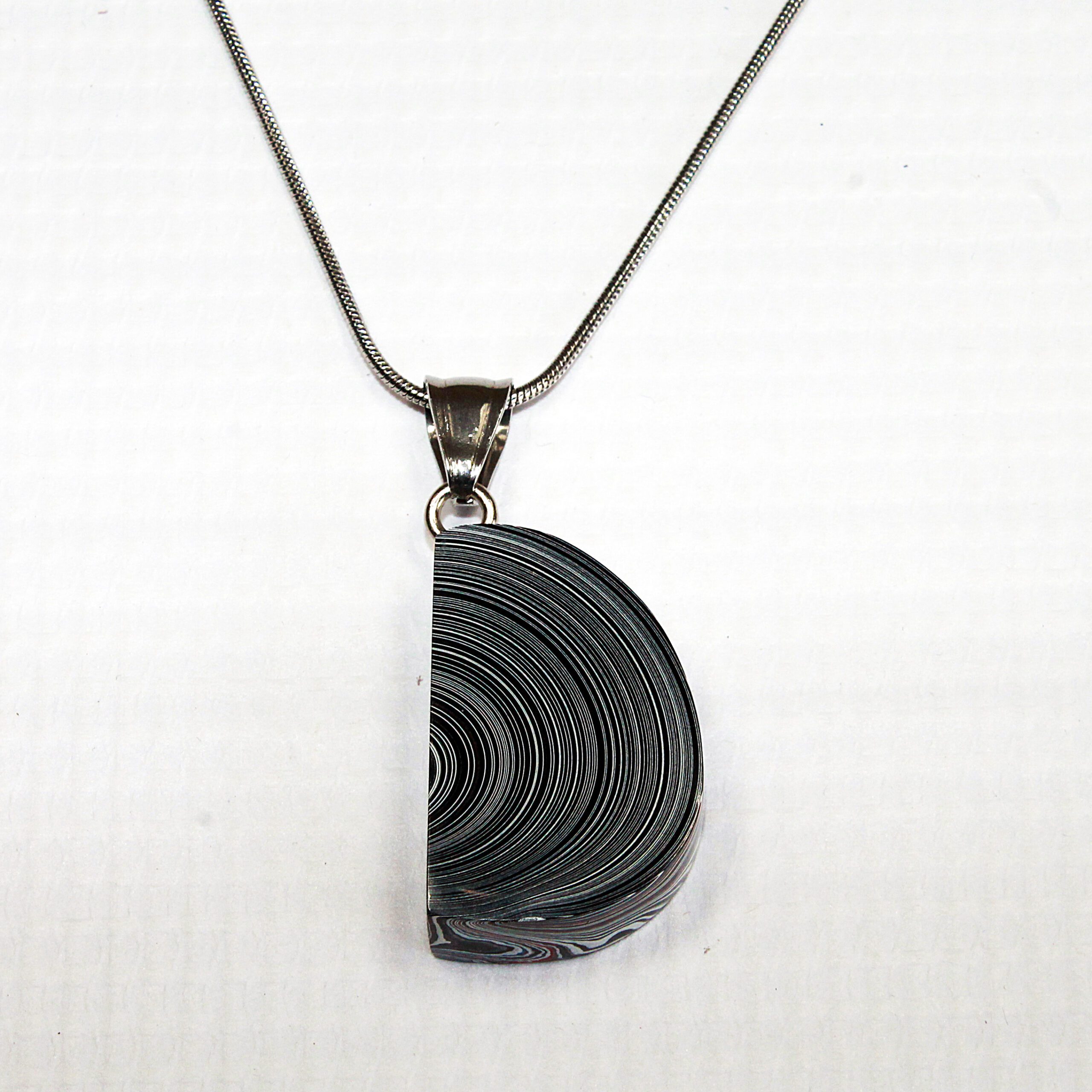 Half-circle pendant on a silver necklace.
