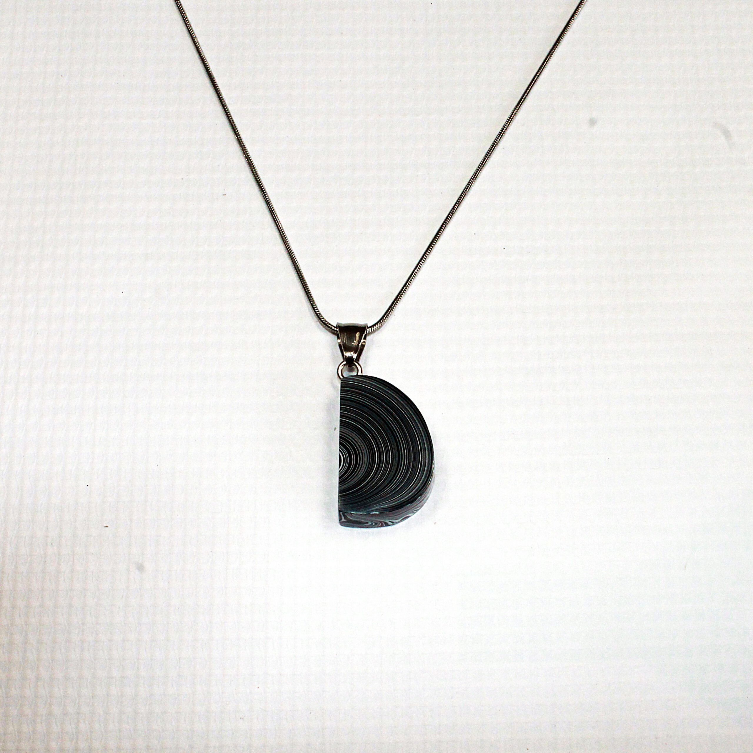Silver chain with circular black pendant.