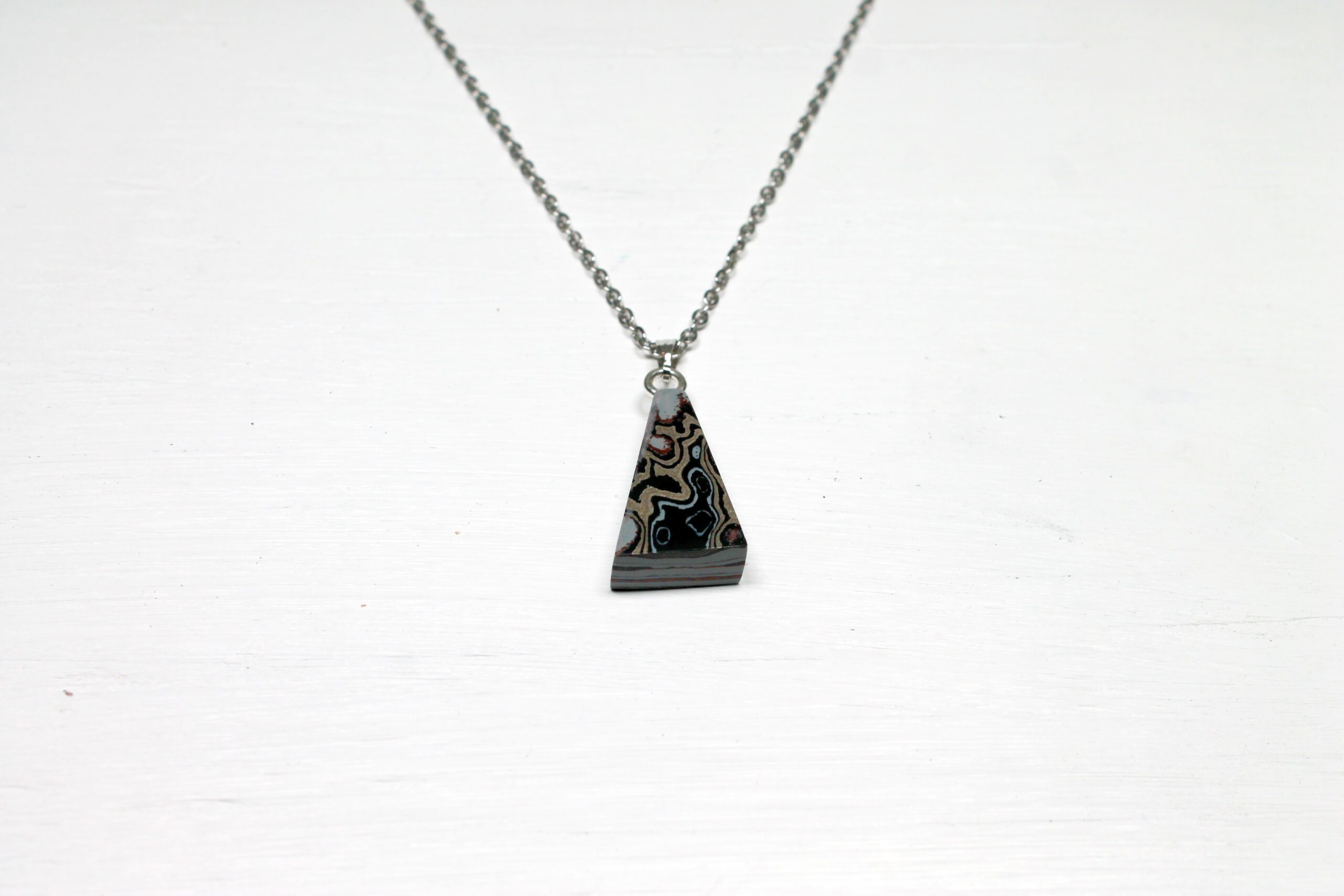 Triangular pendant necklace on plain background.