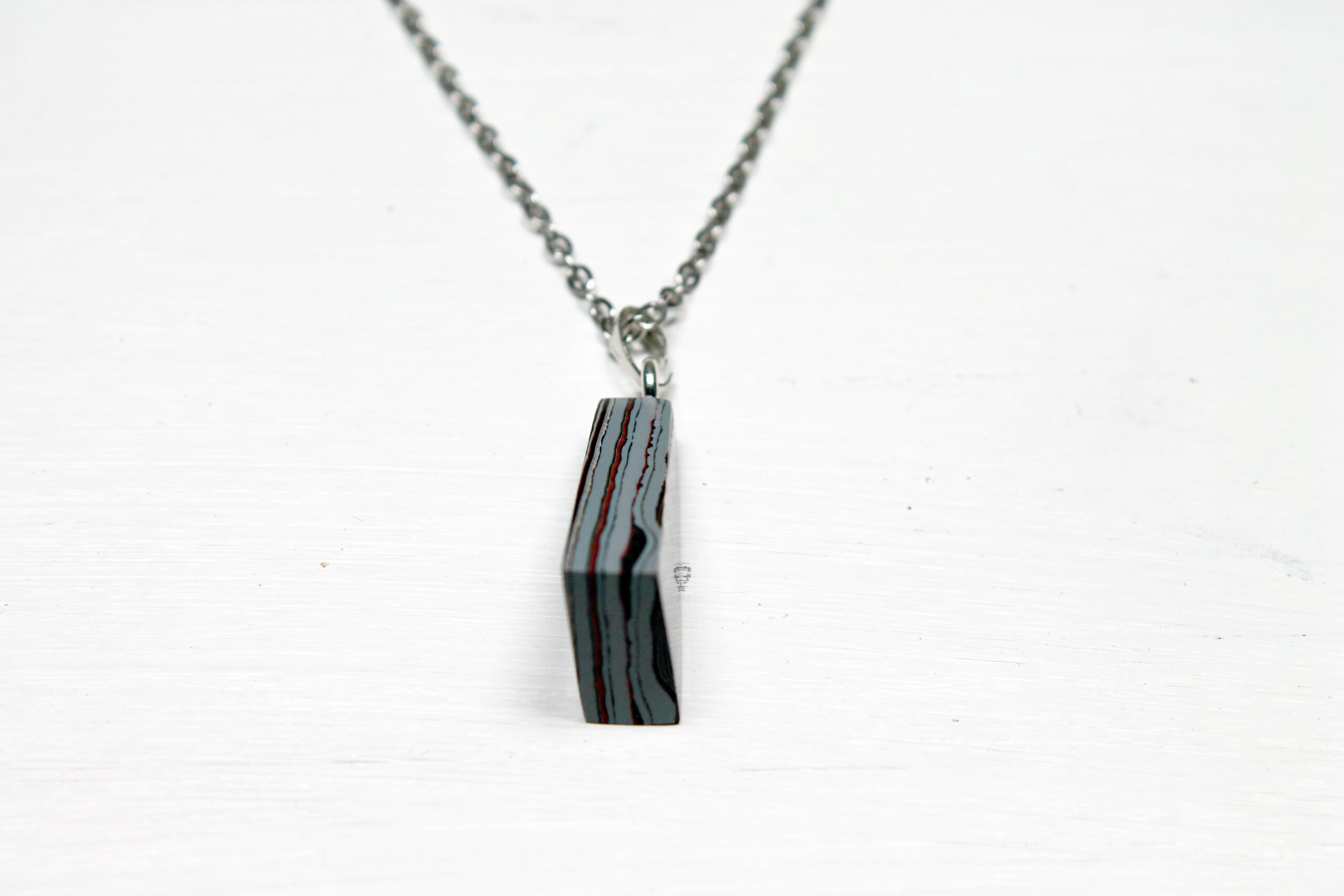 Pendant necklace with striped rectangular charm.