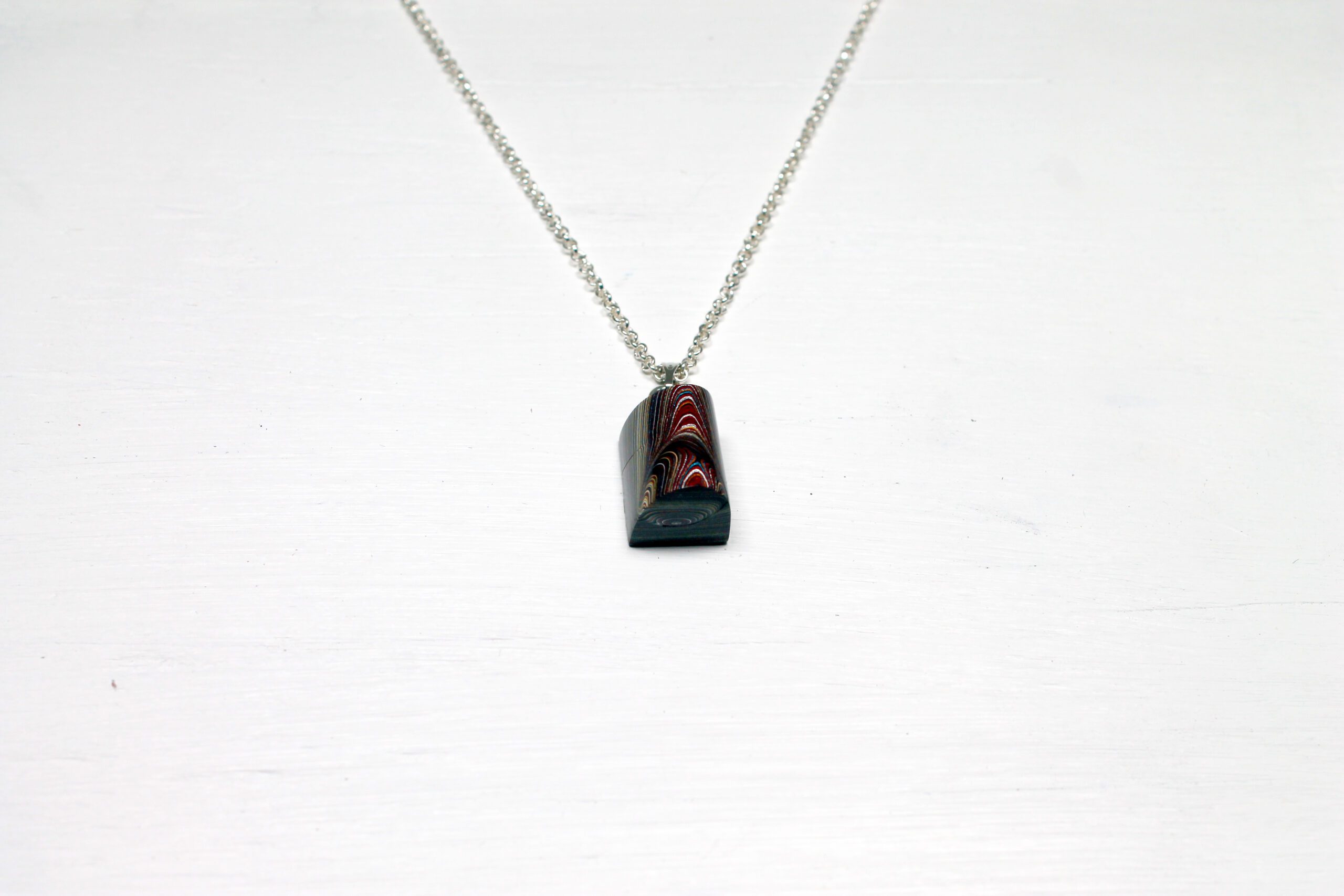 Silver chain with red rectangular pendant.