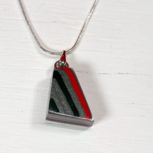 Triangular pendant with red and black design.