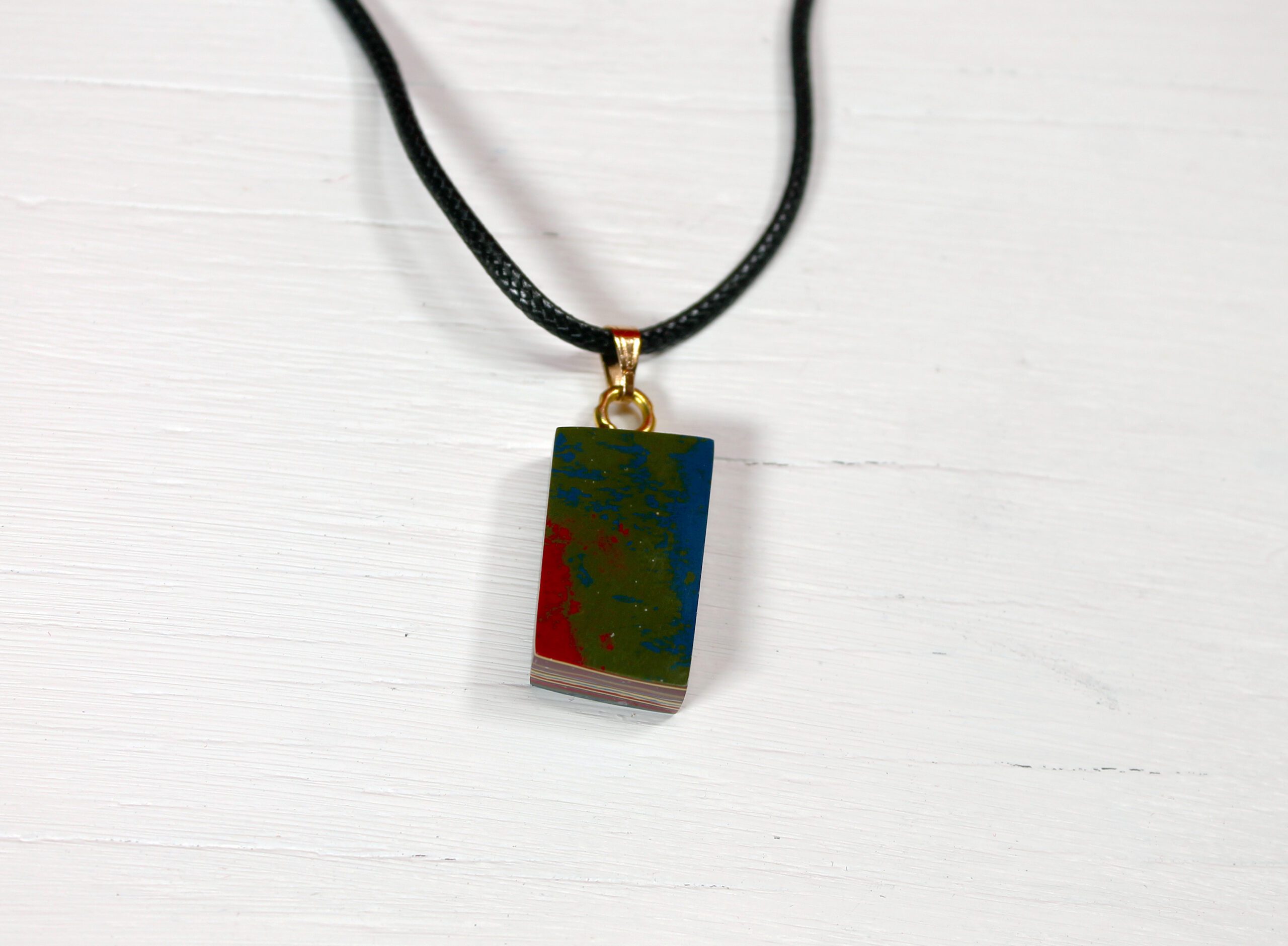 Colorful pendant on black cord necklace.