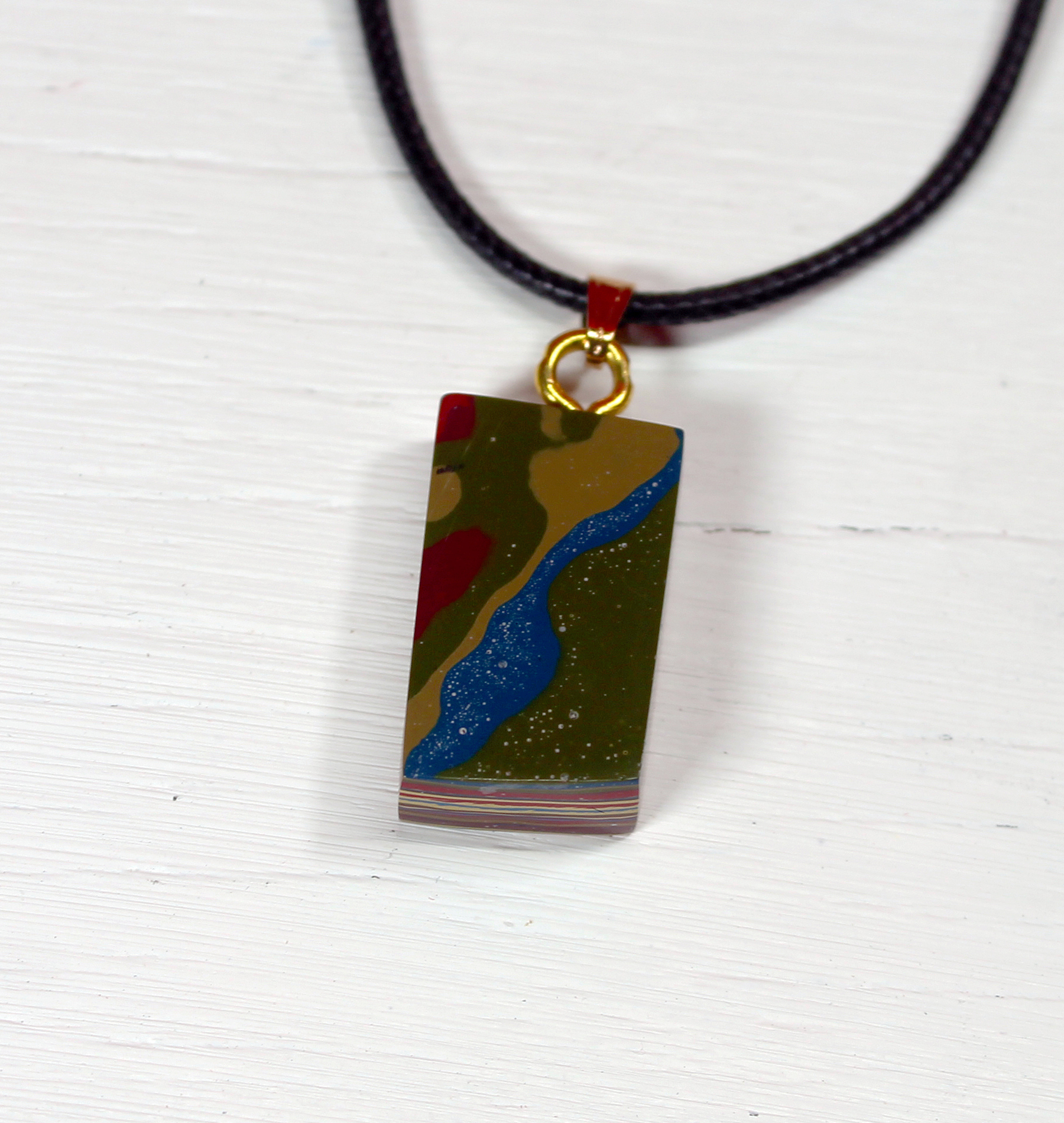 Colorful abstract pendant on black cord necklace.
