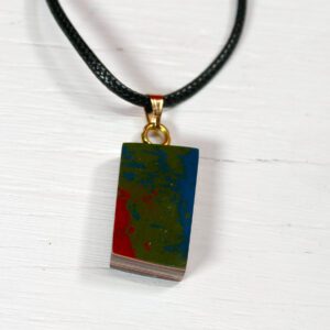 Colorful pendant on black cord necklace.