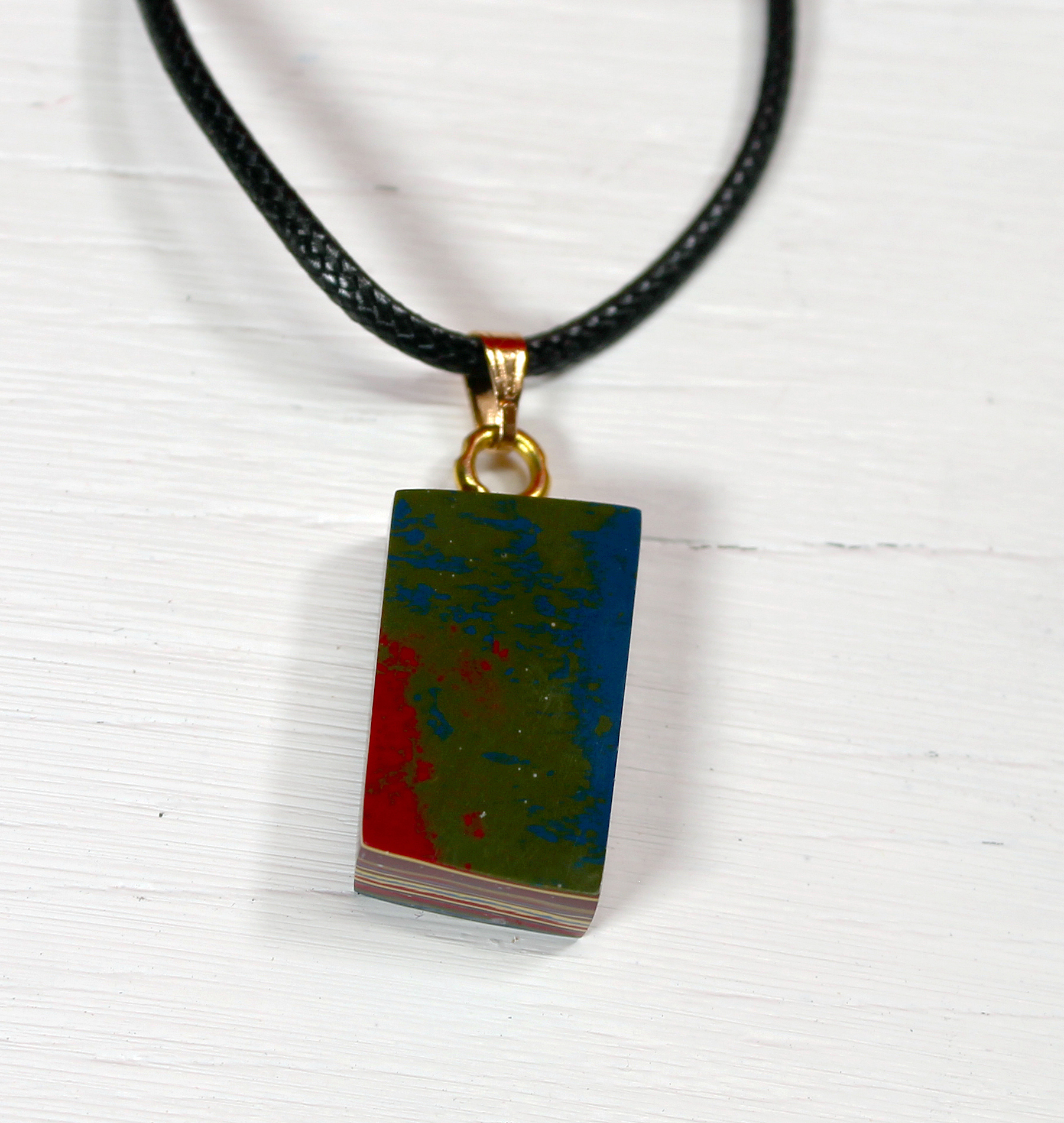Colorful pendant on black cord necklace.