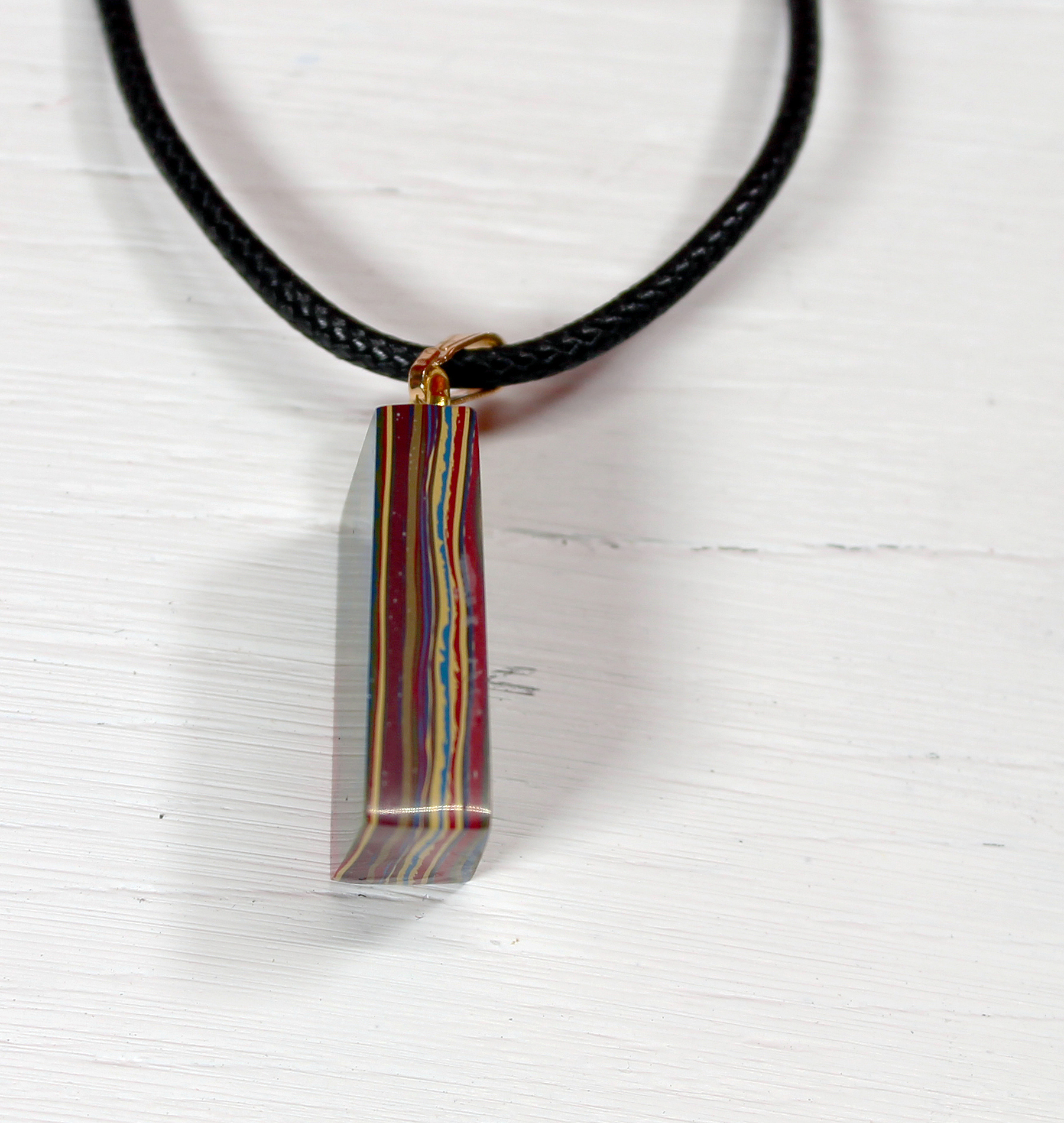 Colorful pendant on black cord necklace.