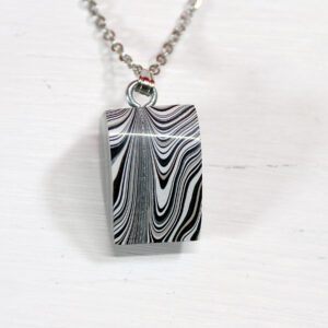 Black and white patterned pendant on chain.