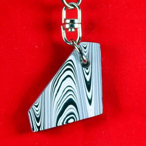 Striped keychain pendant on red background.