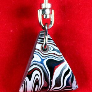 Striped triangular keychain against red background.