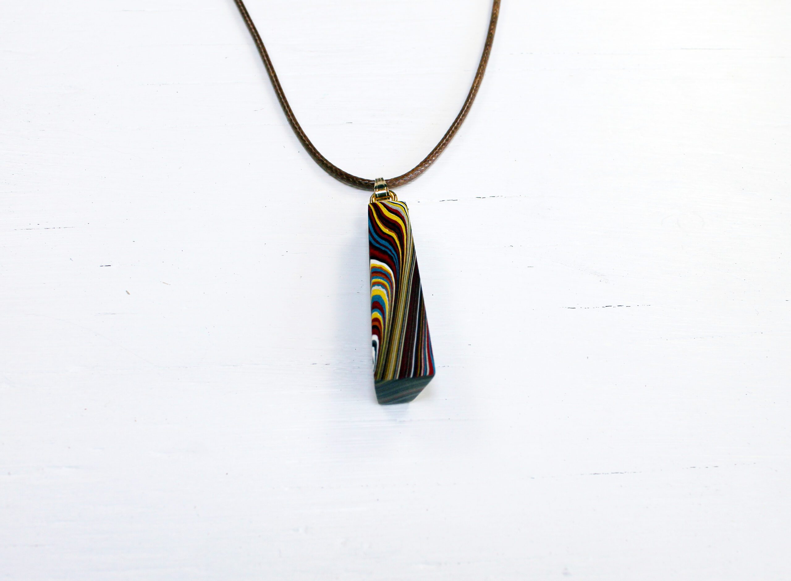 Colorful striped pendant on leather necklace.