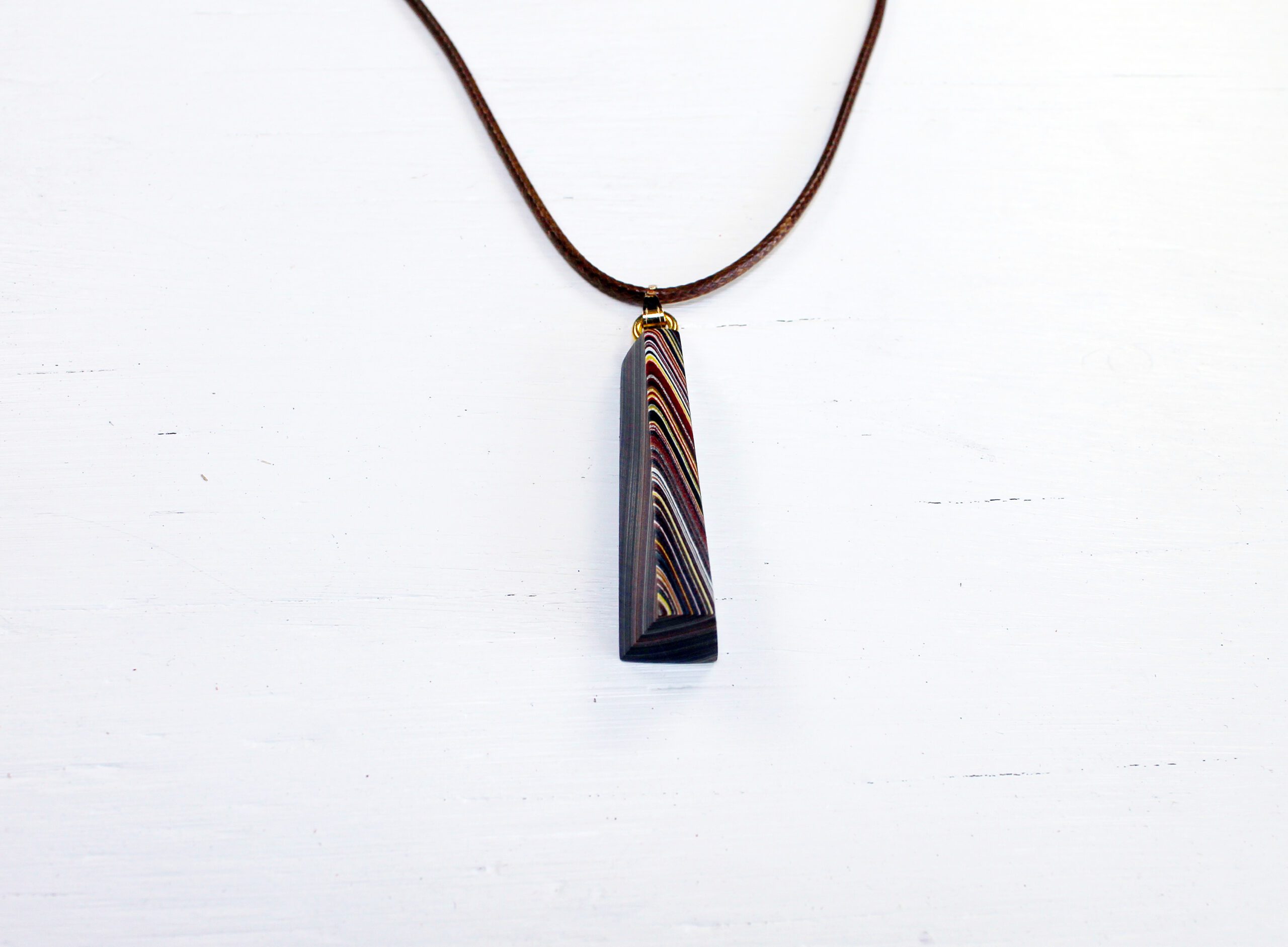 Striped pendant on brown cord necklace.