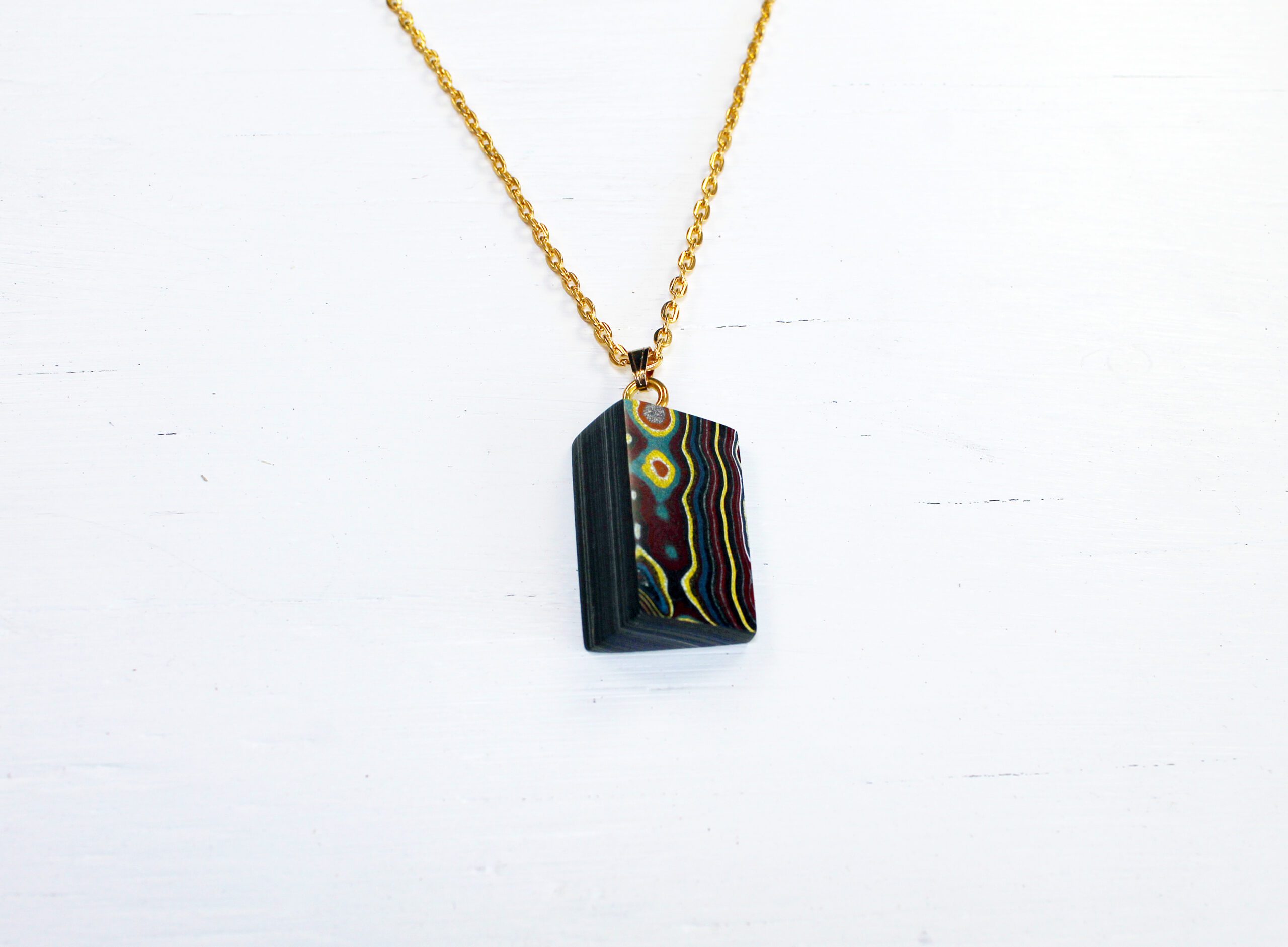 Colorful pendant on a gold chain necklace.