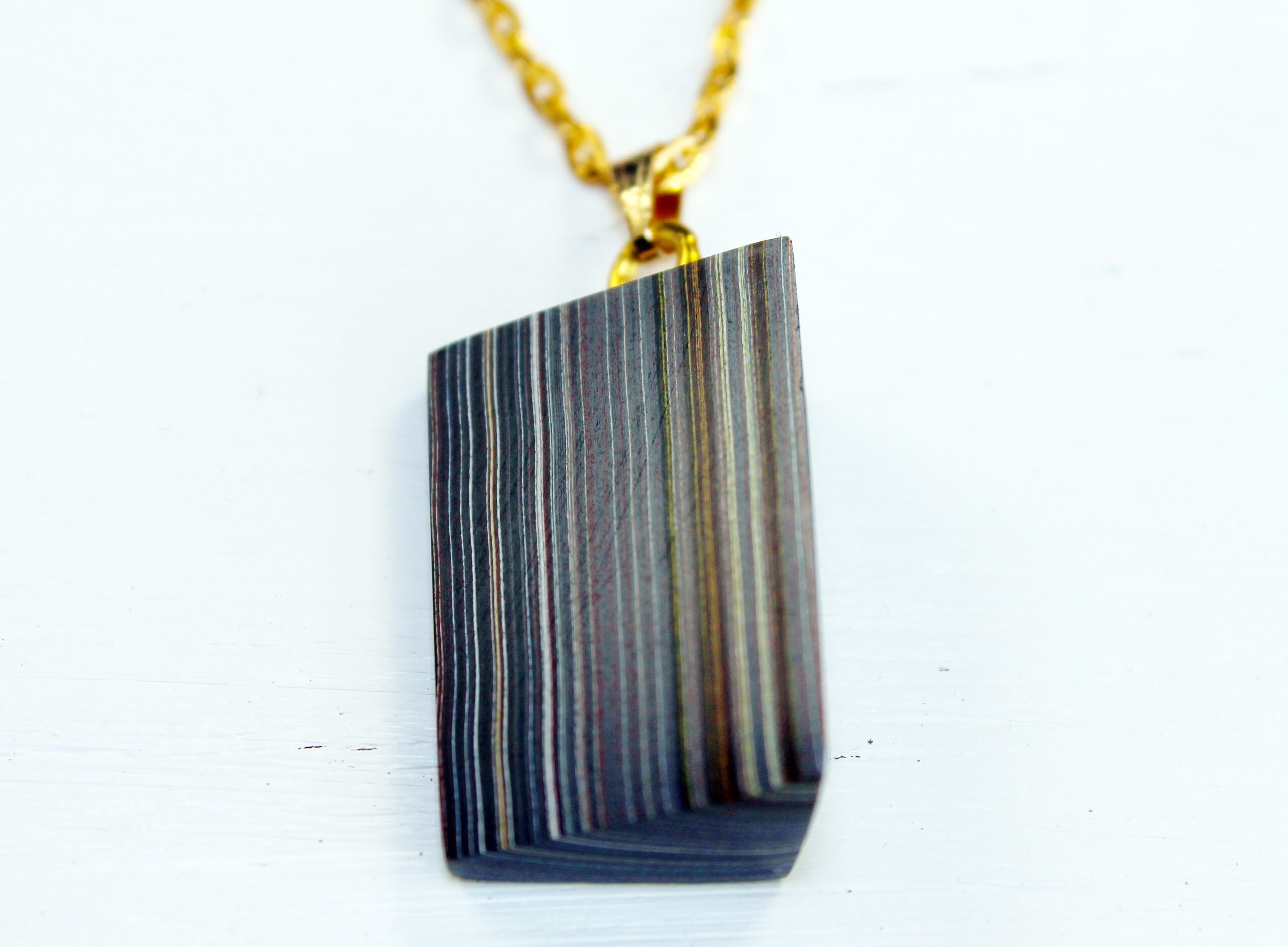 Striped pendant necklace on gold chain.