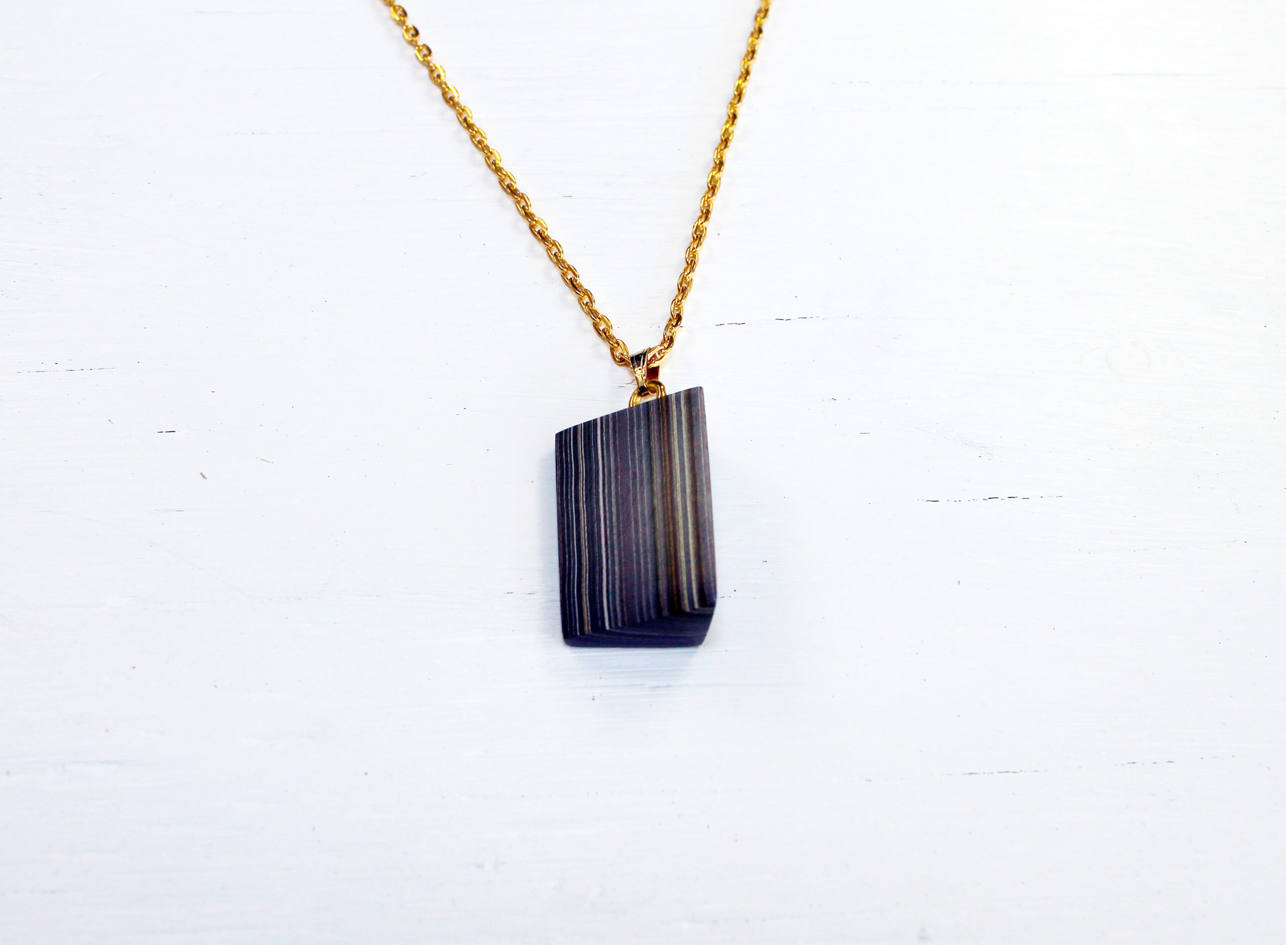 Gold chain with striped rectangular pendant.