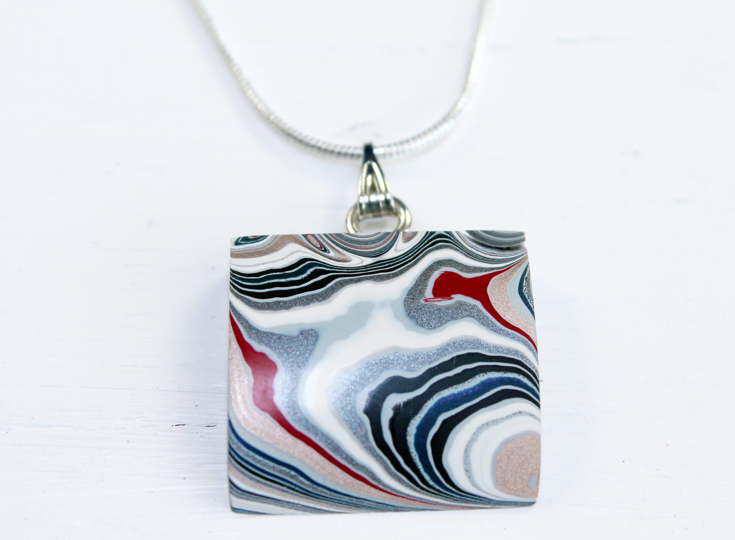 Pendant with abstract swirl pattern design.