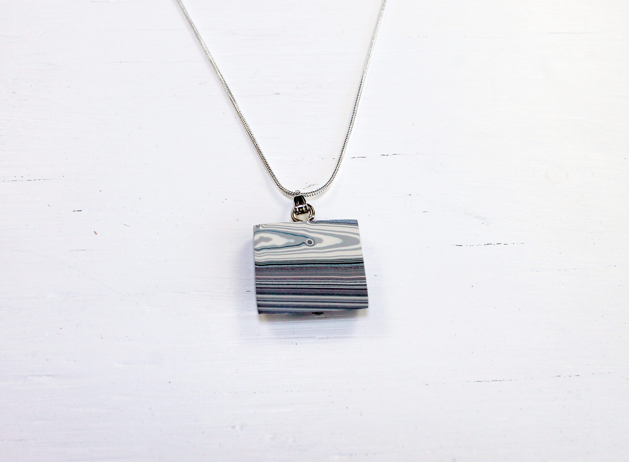 Square pendant on a silver chain necklace.