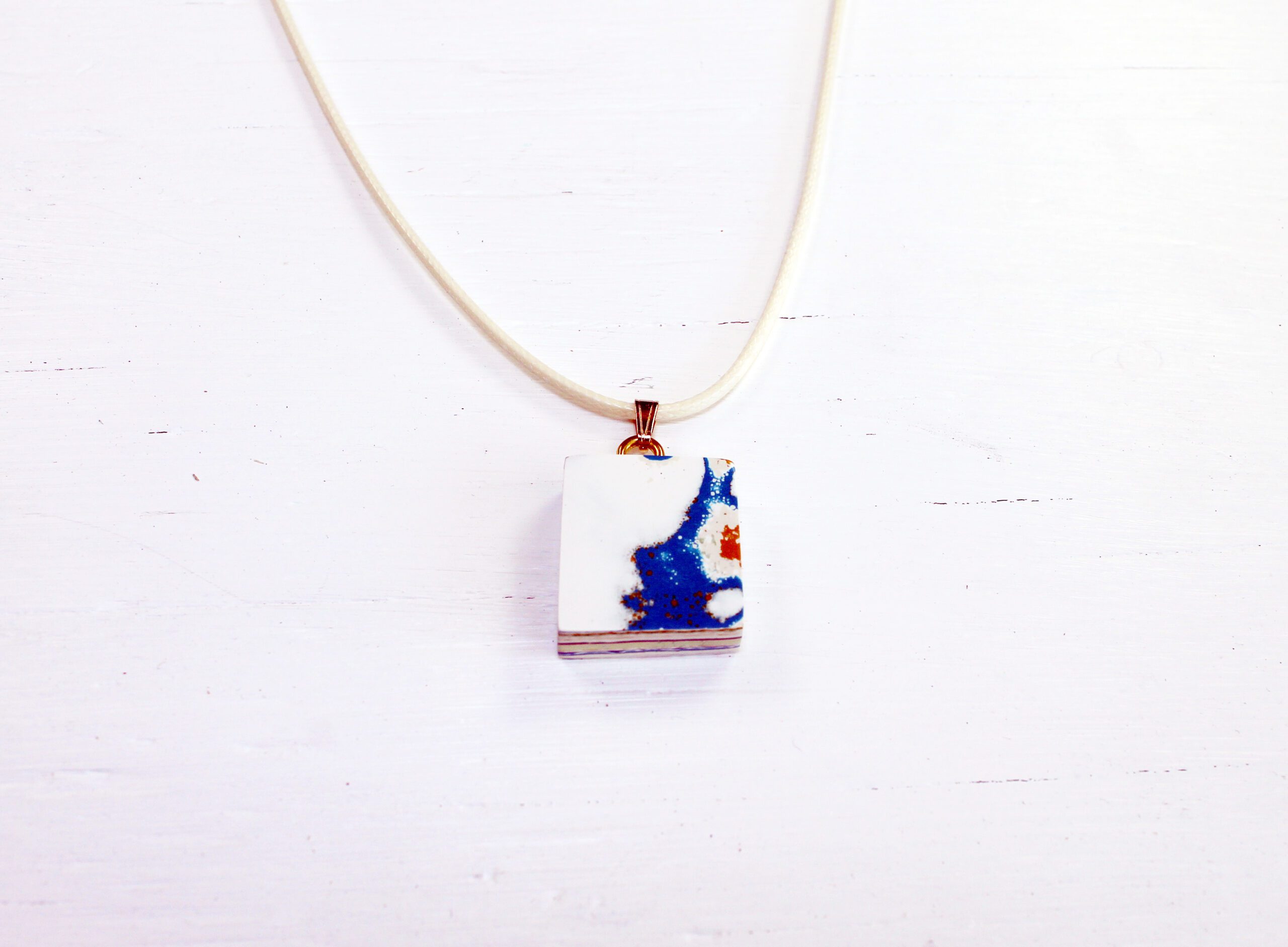 White necklace with abstract blue pendant.