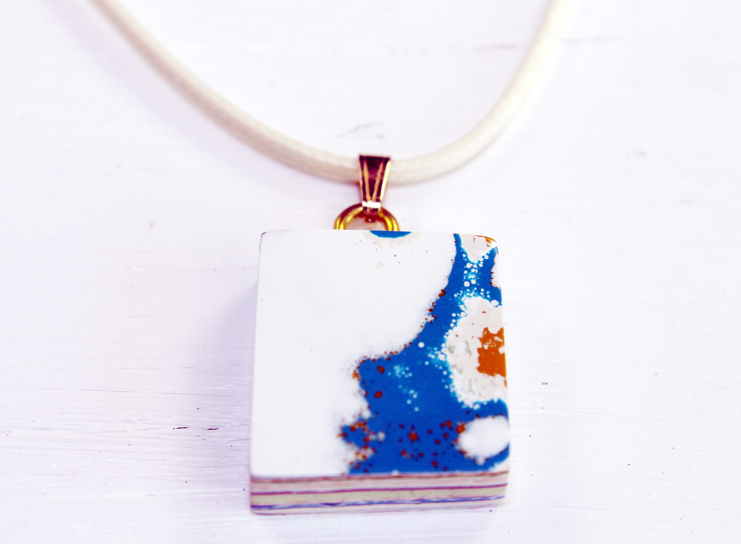 Square pendant with abstract blue design.