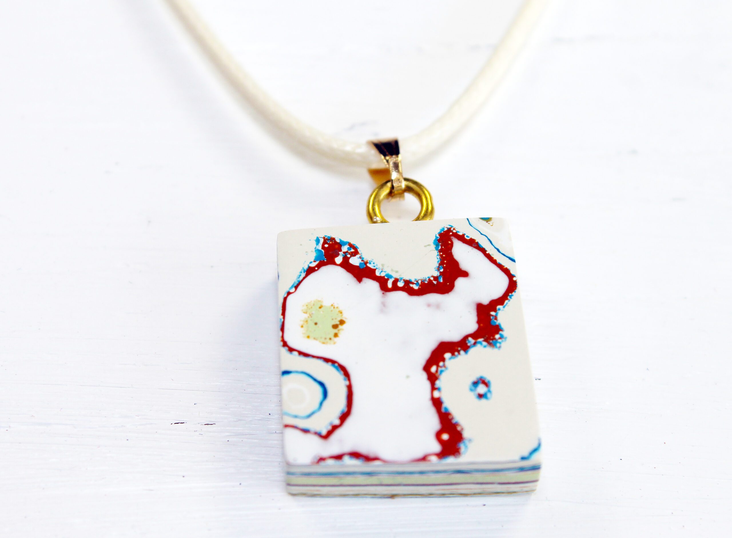 Rectangular pendant with abstract design on necklace.