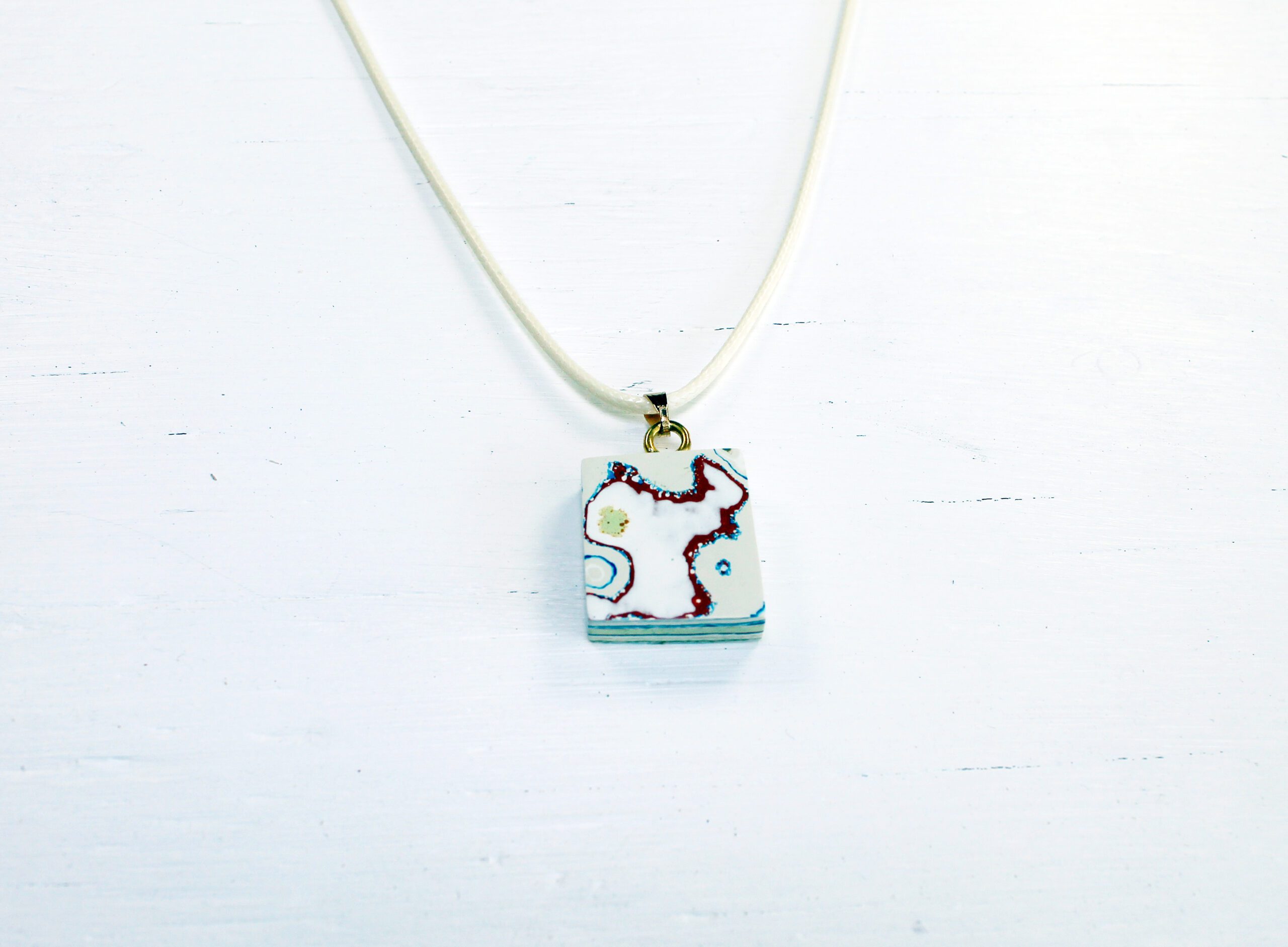 Abstract pendant on white necklace chain.