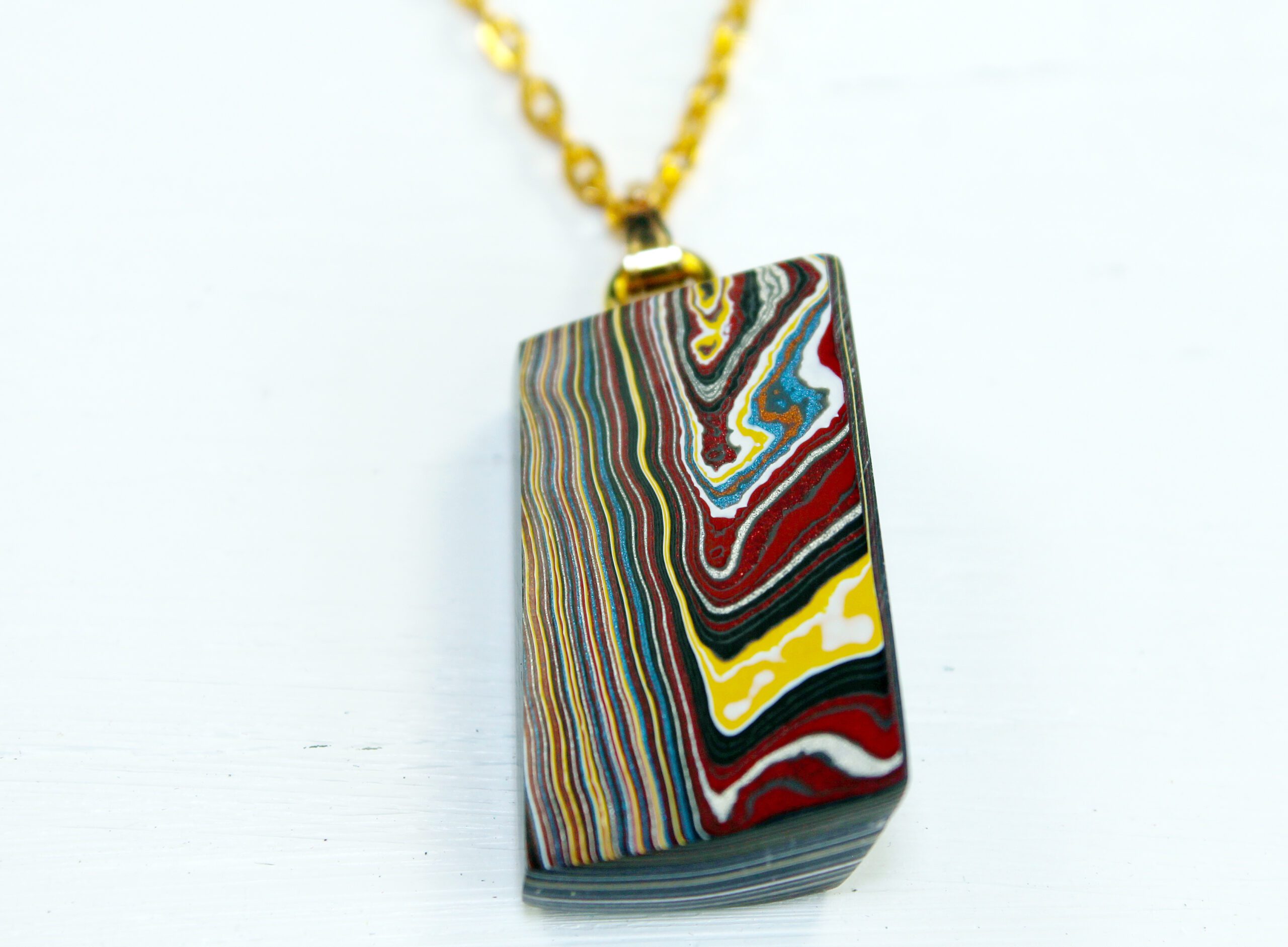 Colorful layered pendant on gold chain.