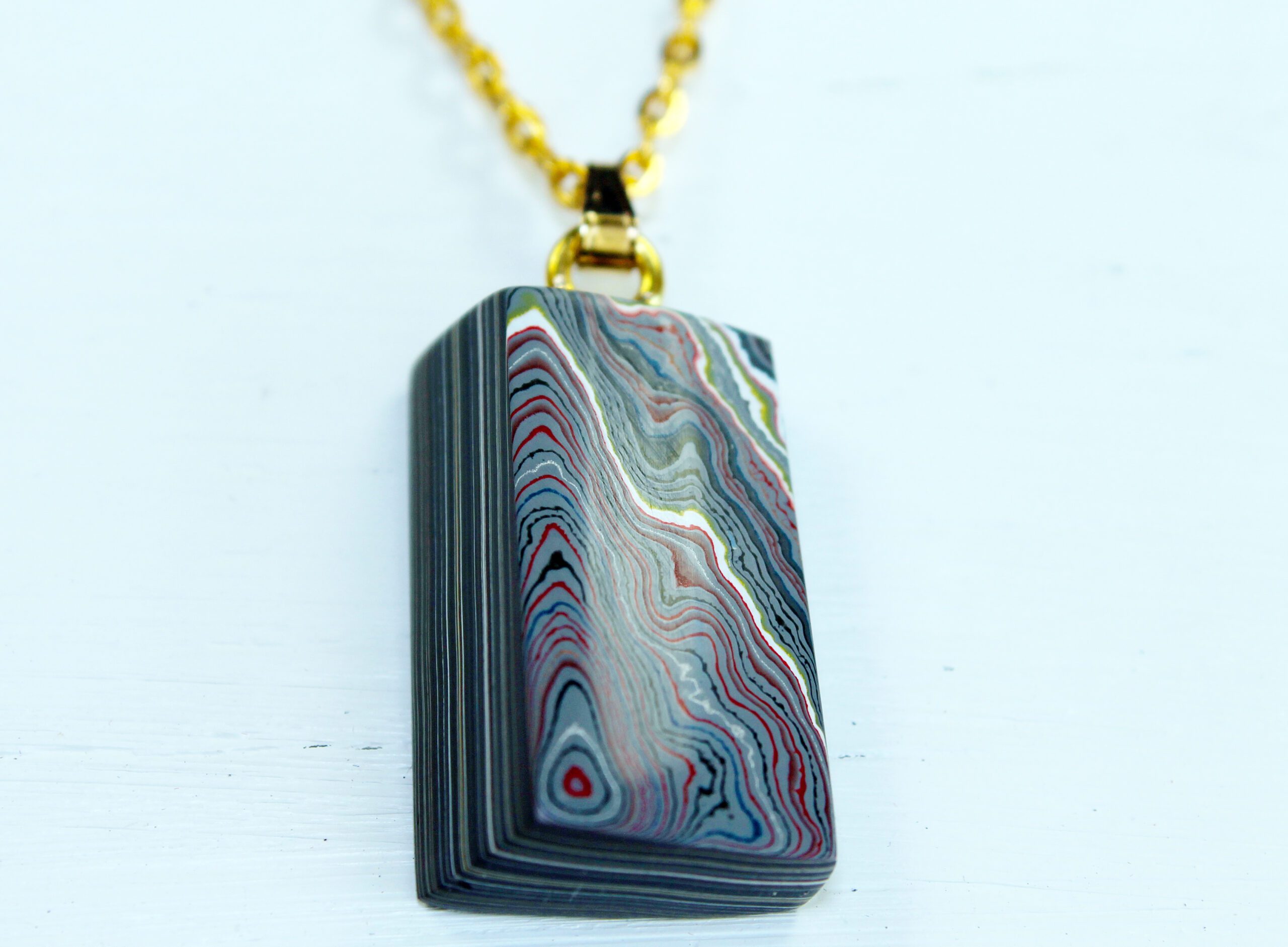 Colorful layered stone pendant with gold chain.