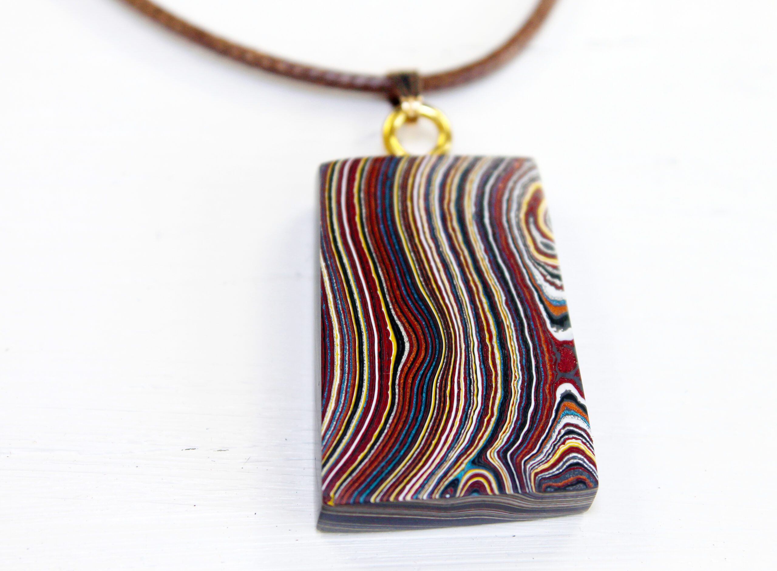 Rectangular pendant with colorful layered design.