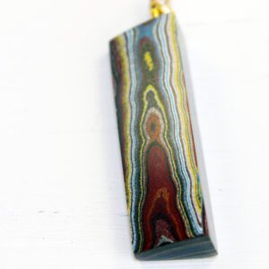 Colorful layered stone pendant on white background.