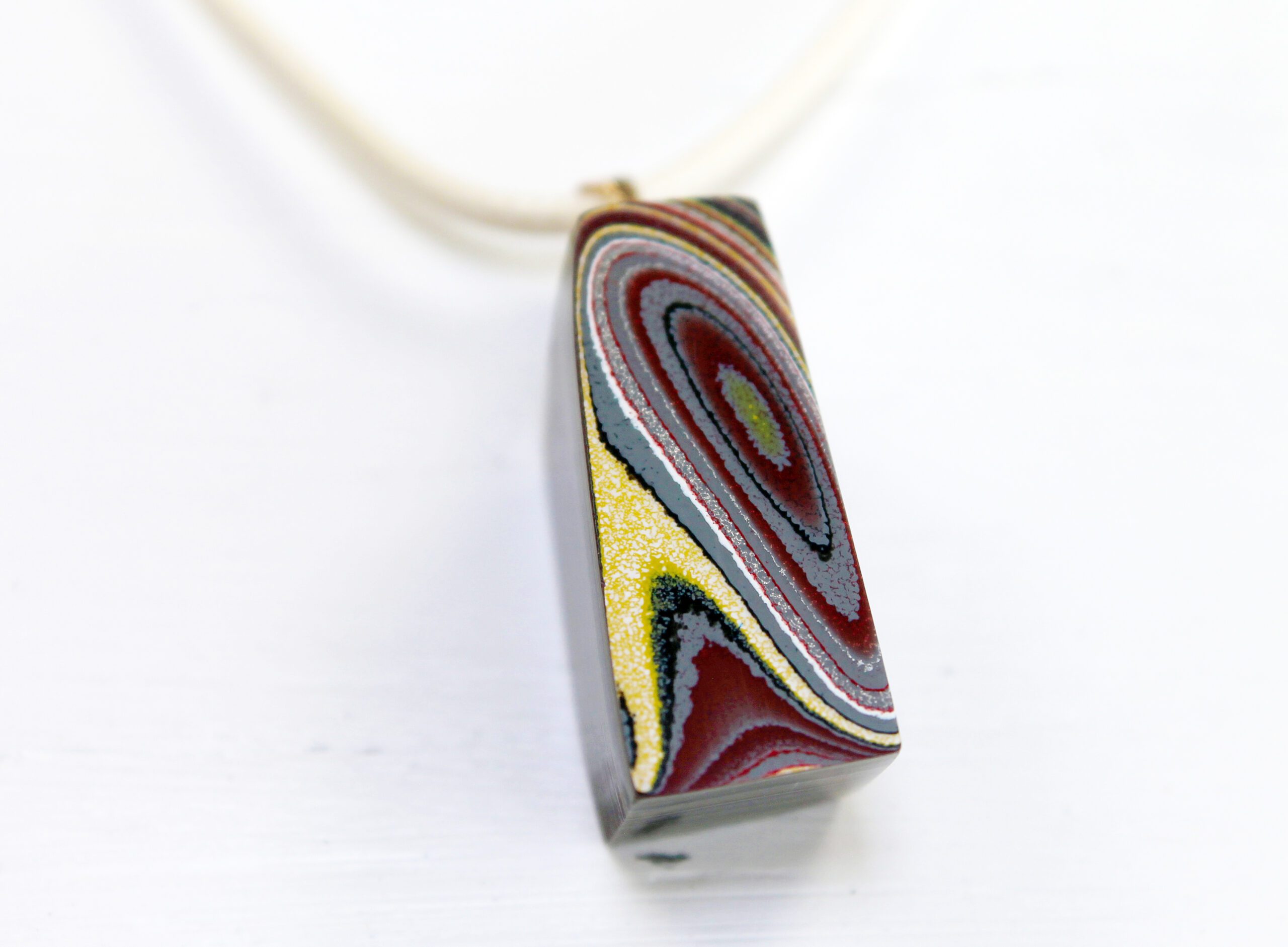 Colorful pendant with swirling patterns on cord.