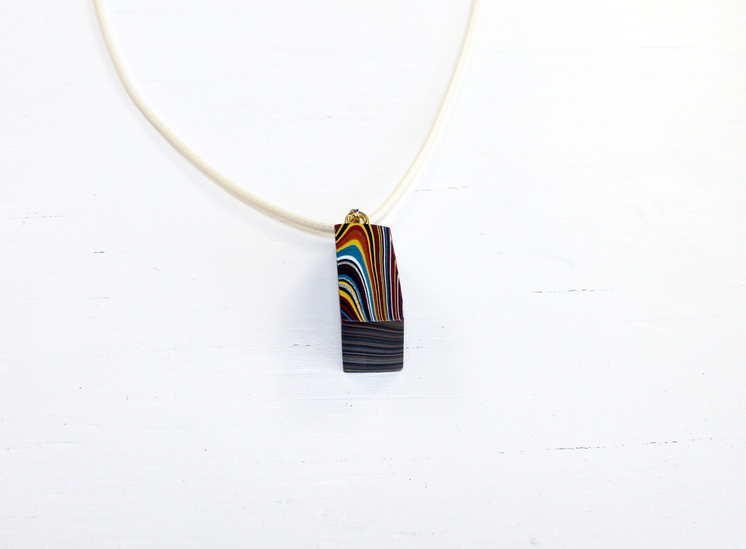 Colorful pendant on a white necklace.