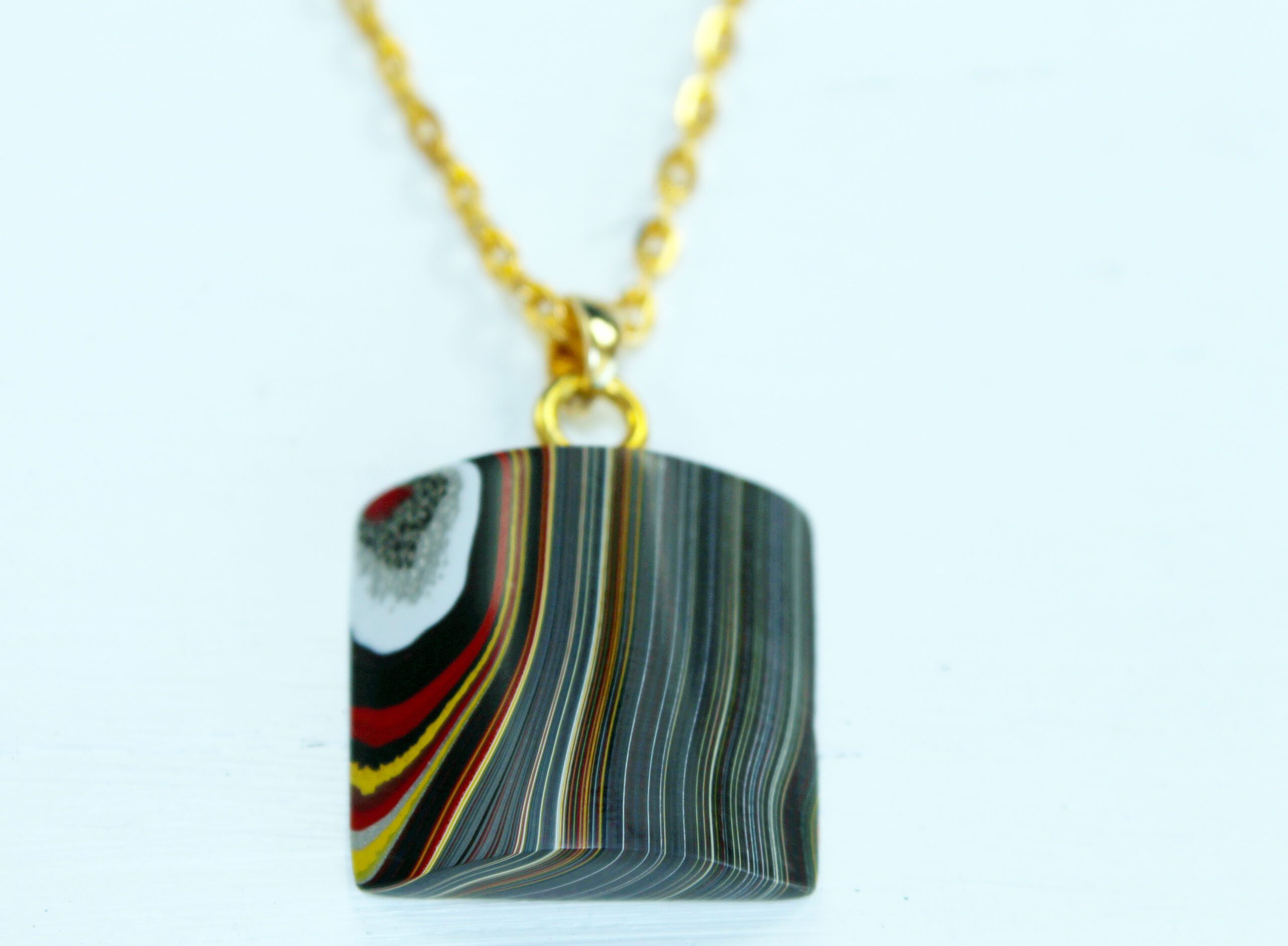 Colorful pendant with striped pattern on chain.