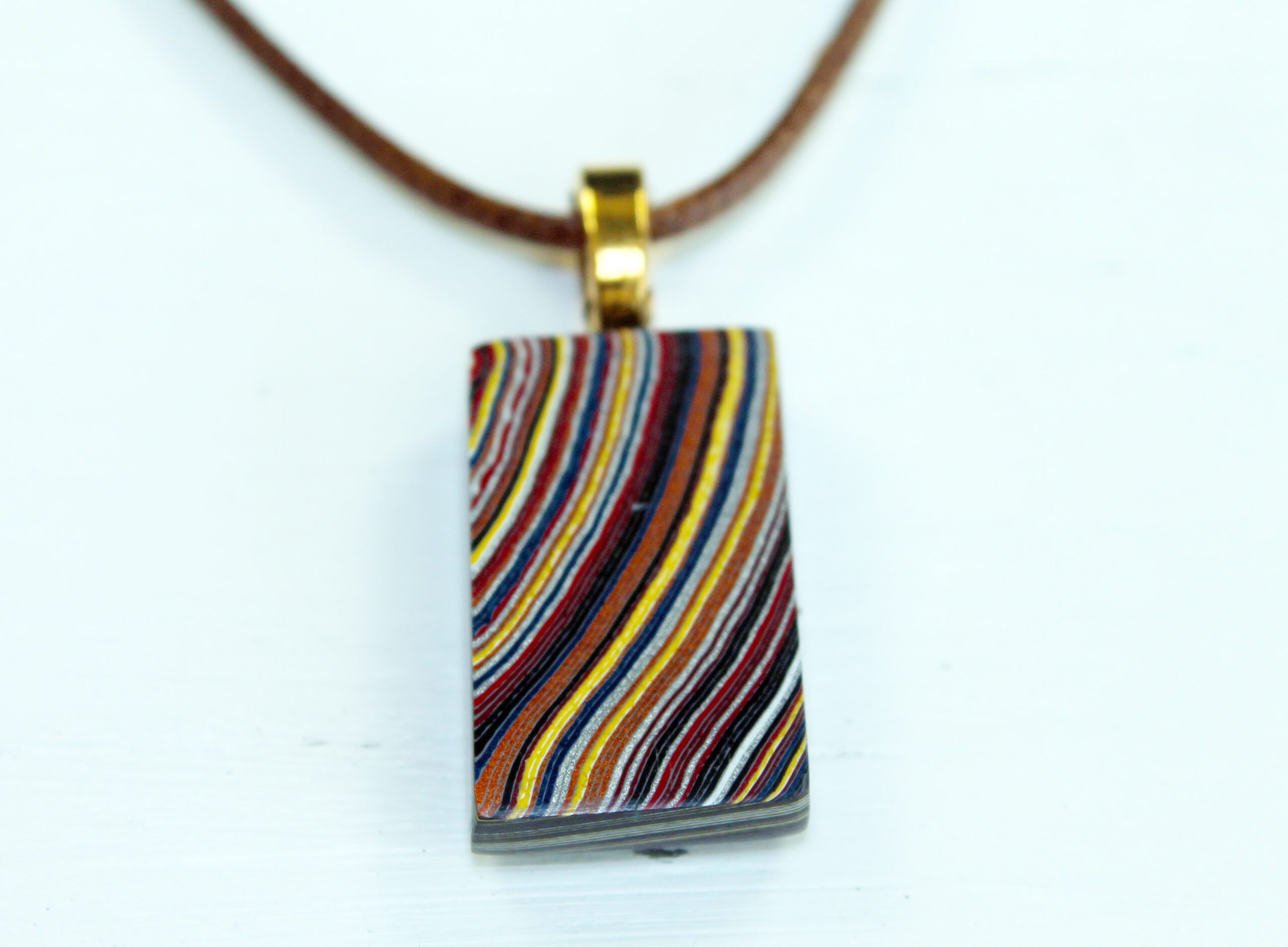 Colorful striped pendant on a brown cord.
