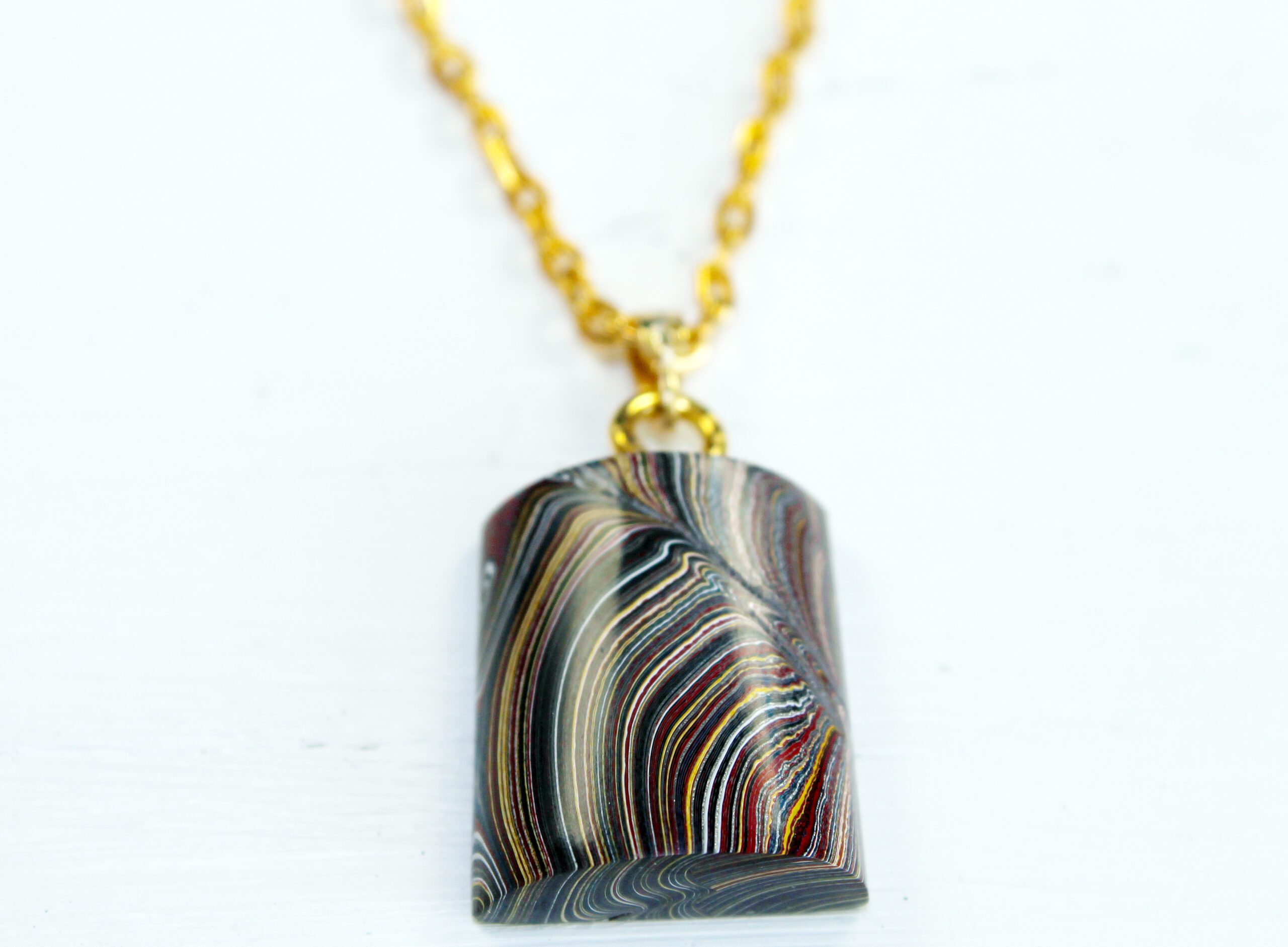 Colorful swirl pendant on gold chain necklace.