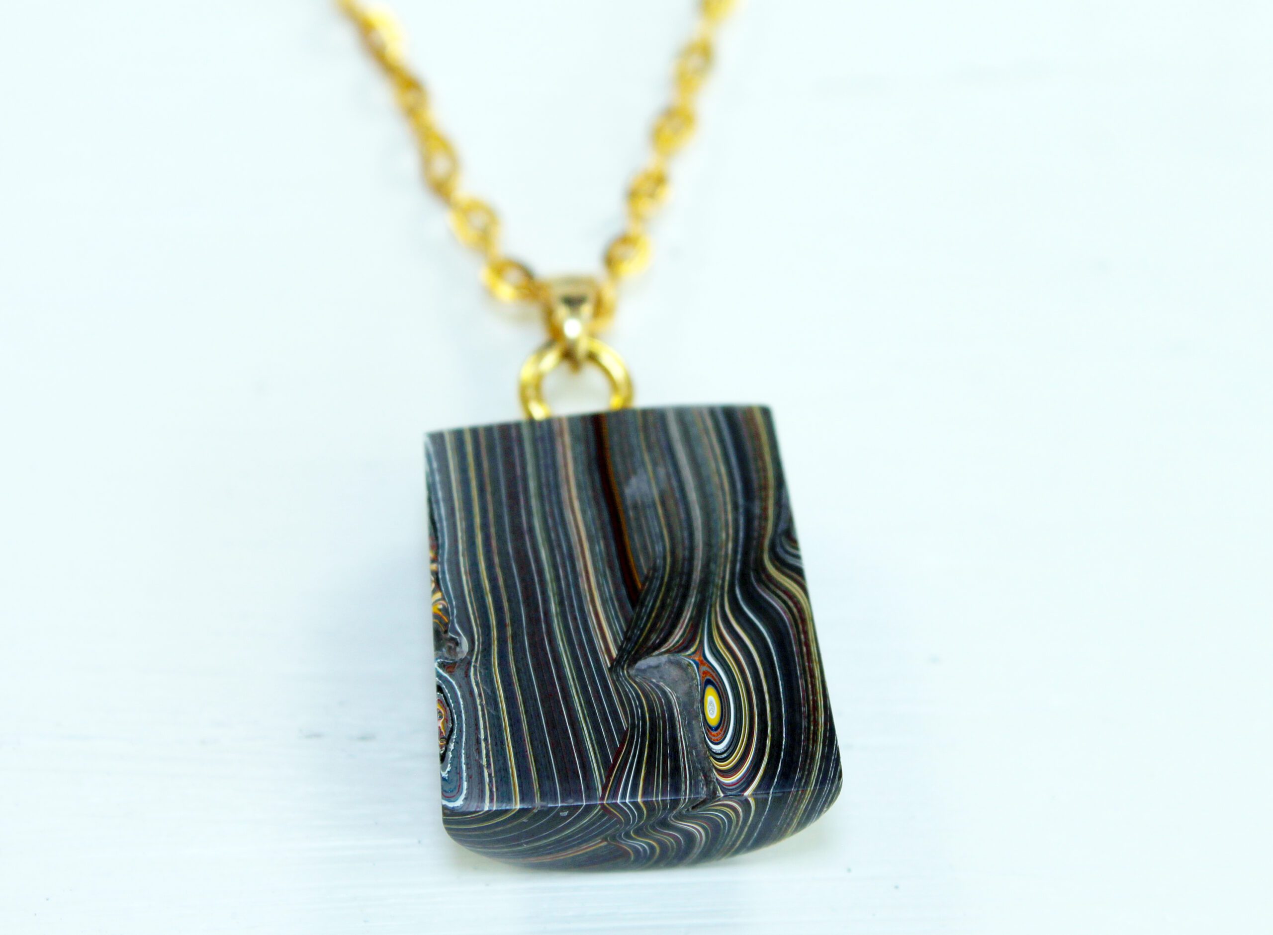 Gold chain with striped stone pendant.