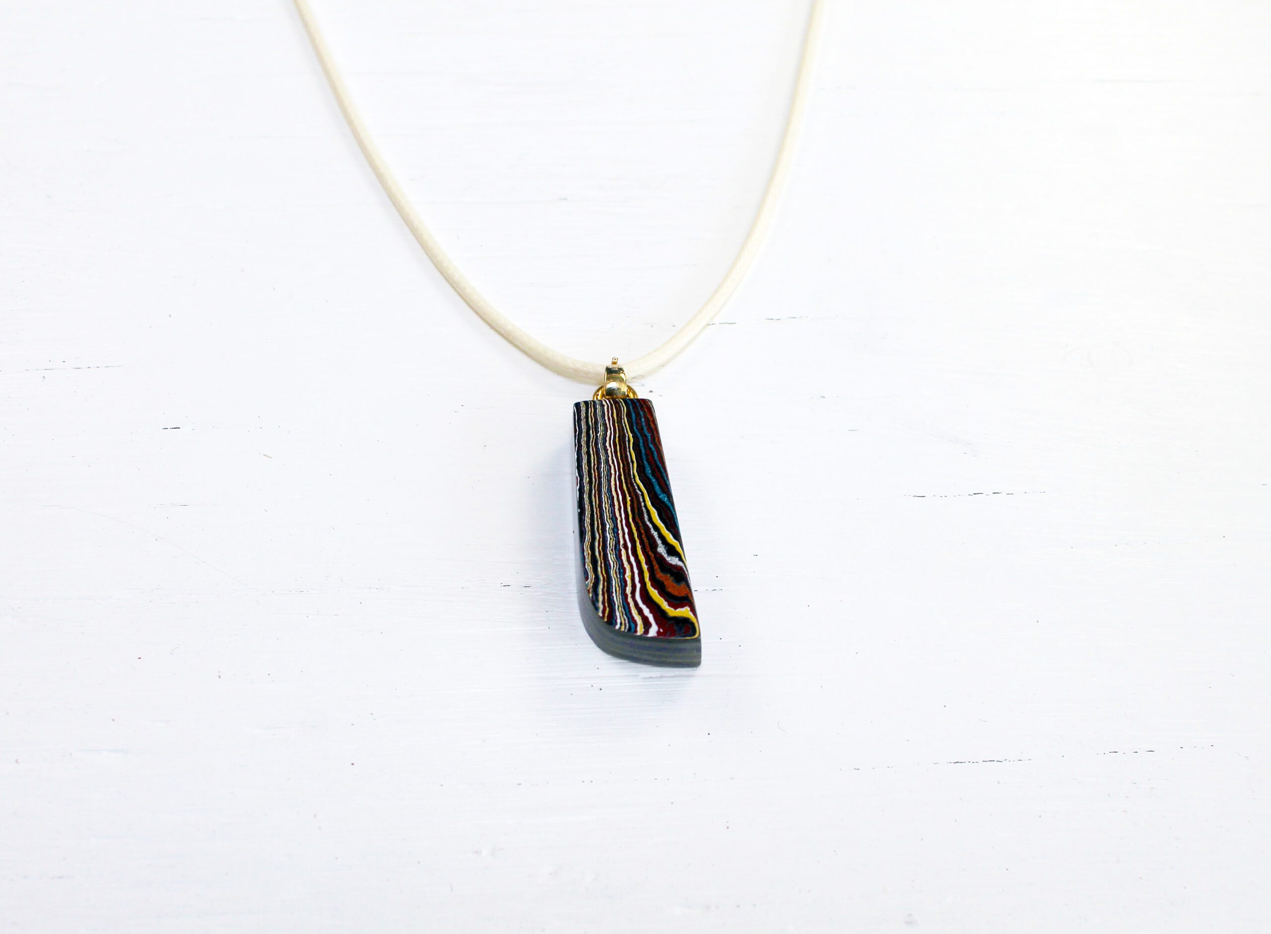 Colorful pendant on a white necklace.