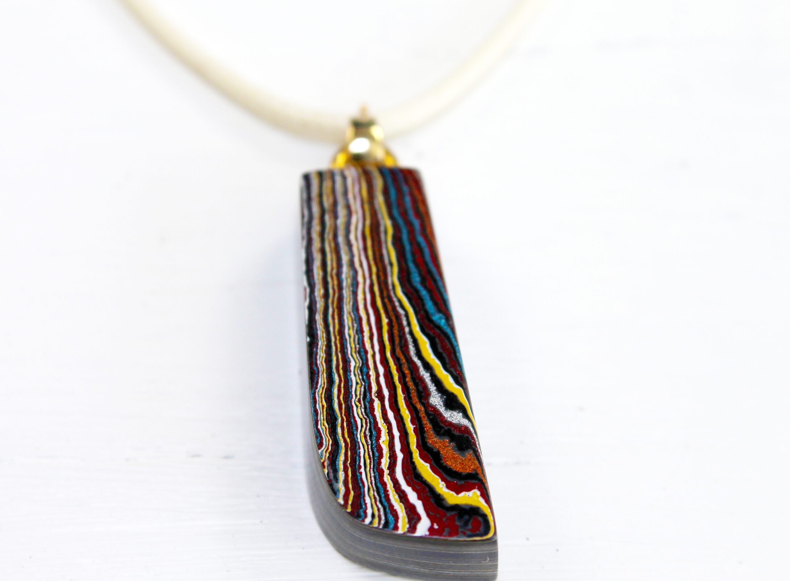 Colorful layered pendant on white background.