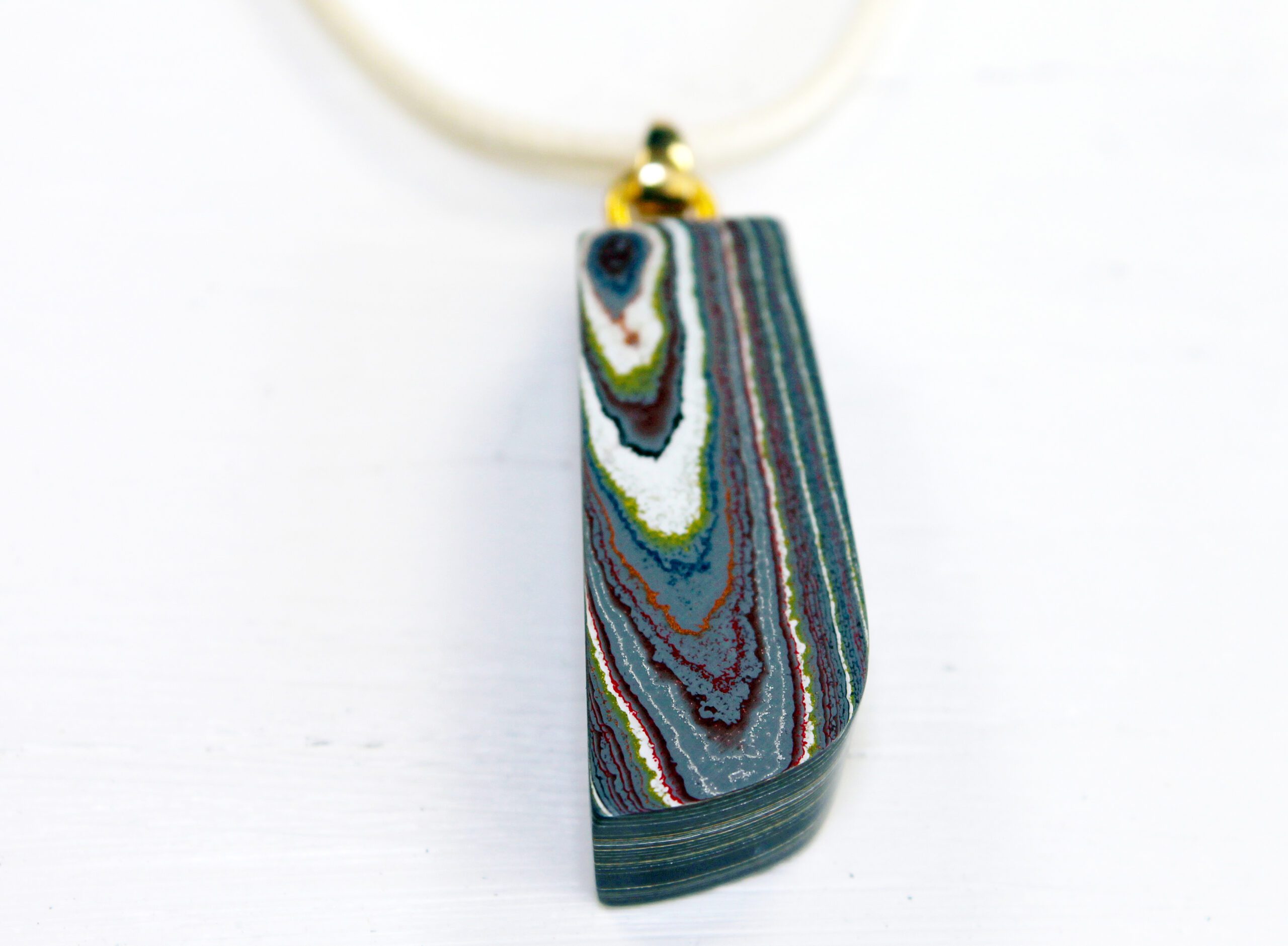 Colorful layered pendant on white background.