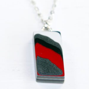 Rectangular pendant with red and black design.