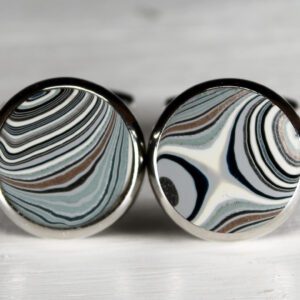 Striped round cufflinks on white surface.